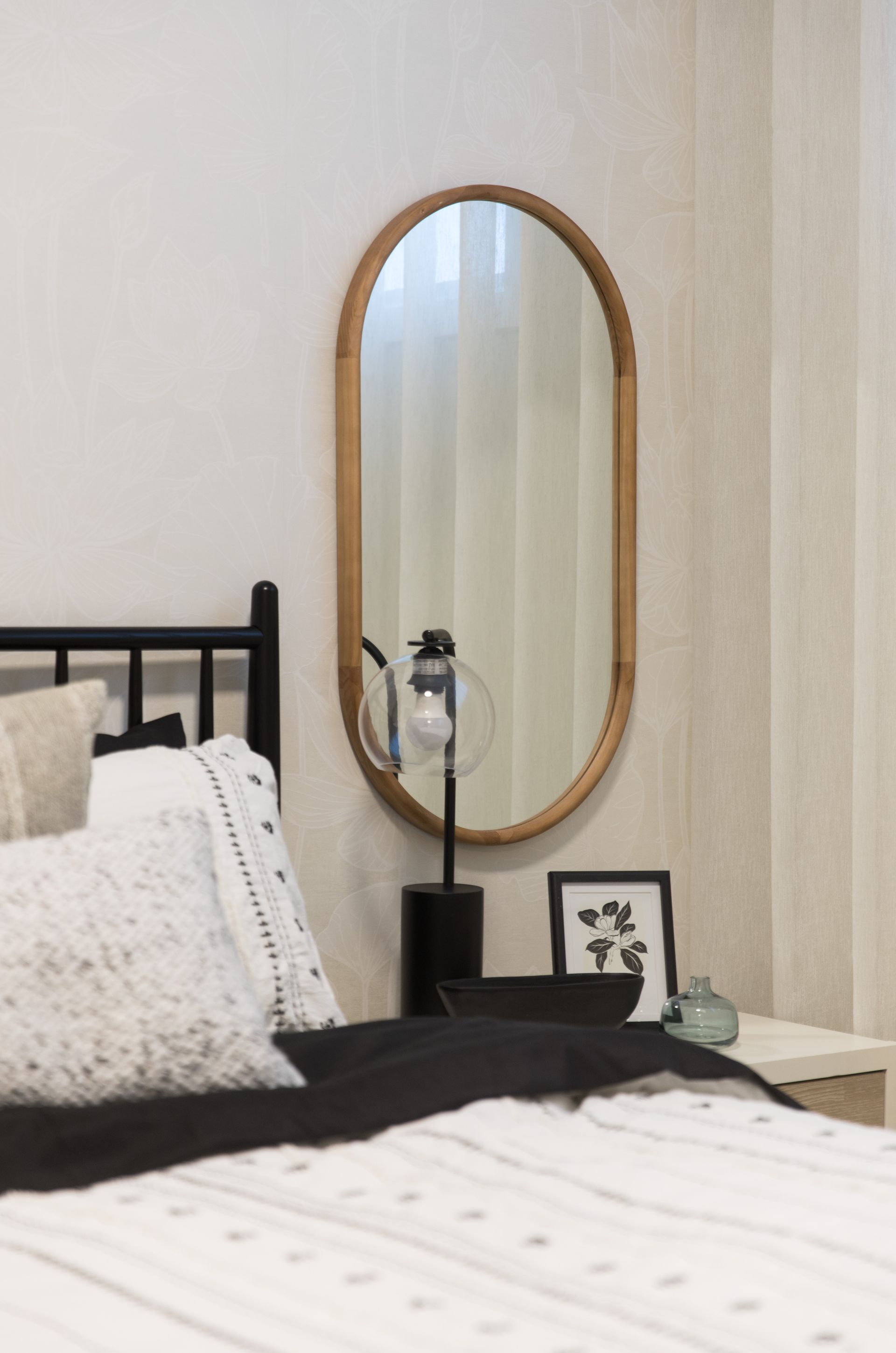 A bedroom with a bed and a mirror on the wall.