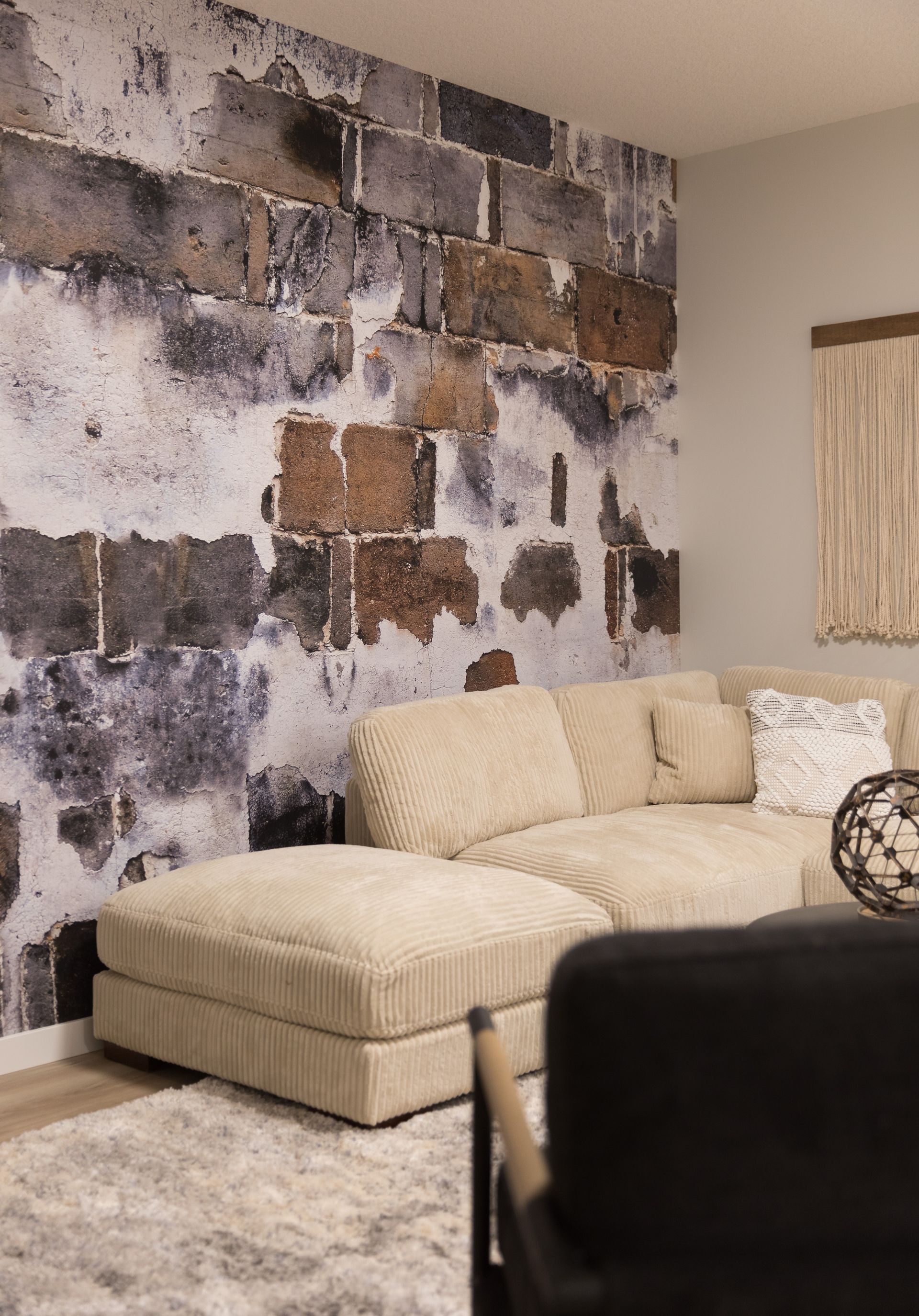 A living room with a couch , chair , rug and a brick wall.