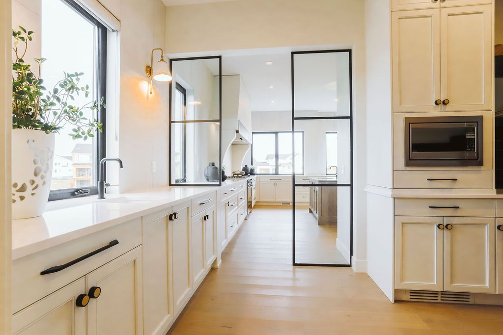 A kitchen with white cabinets , hardwood floors , stainless steel appliances and a sliding glass door.