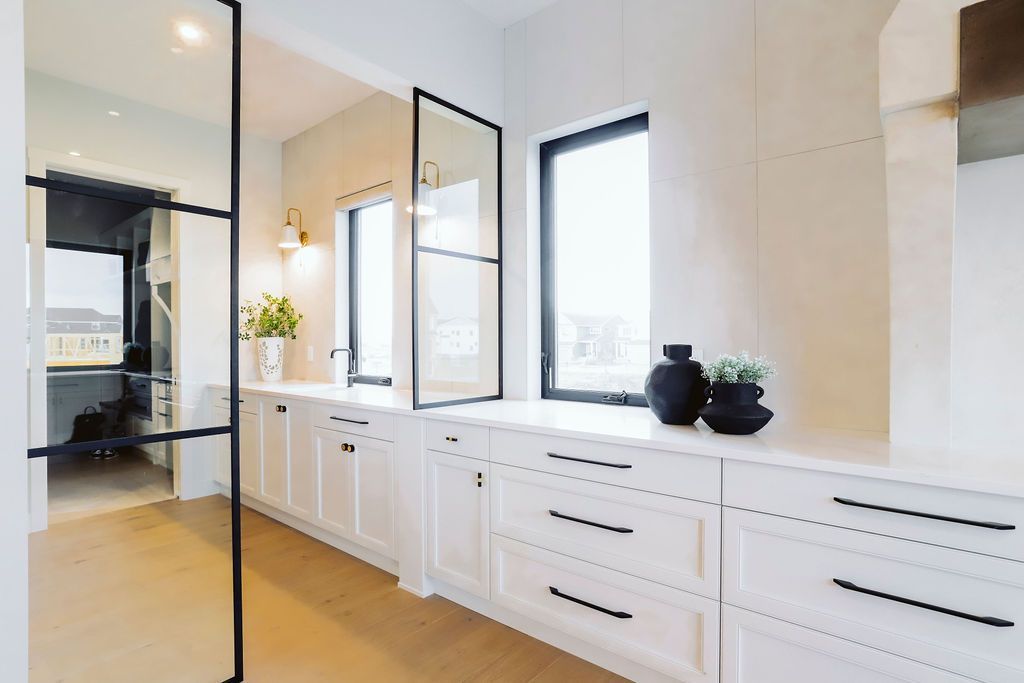 A kitchen with white cabinets and black handles and a glass door.