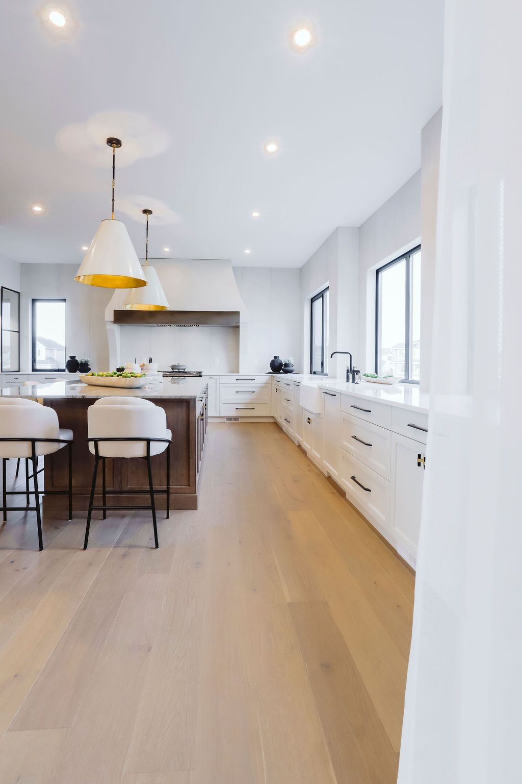 A kitchen with white cabinets , wooden floors , and a large island.