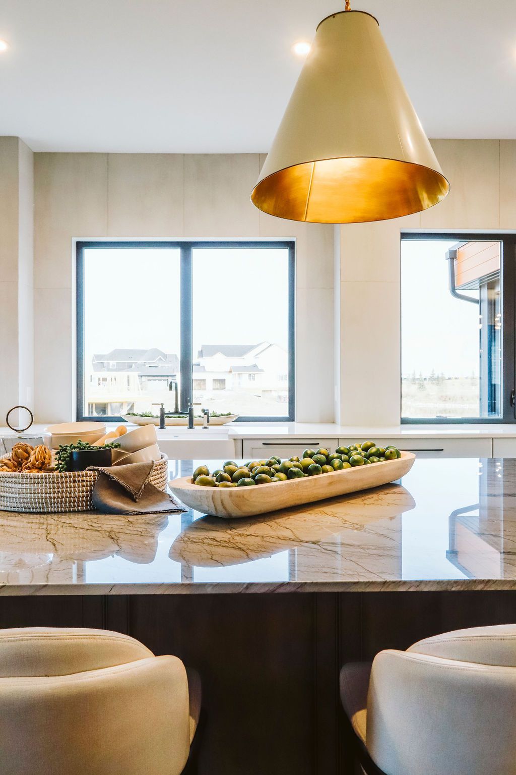 A kitchen with a large island with a bowl of greens on it.