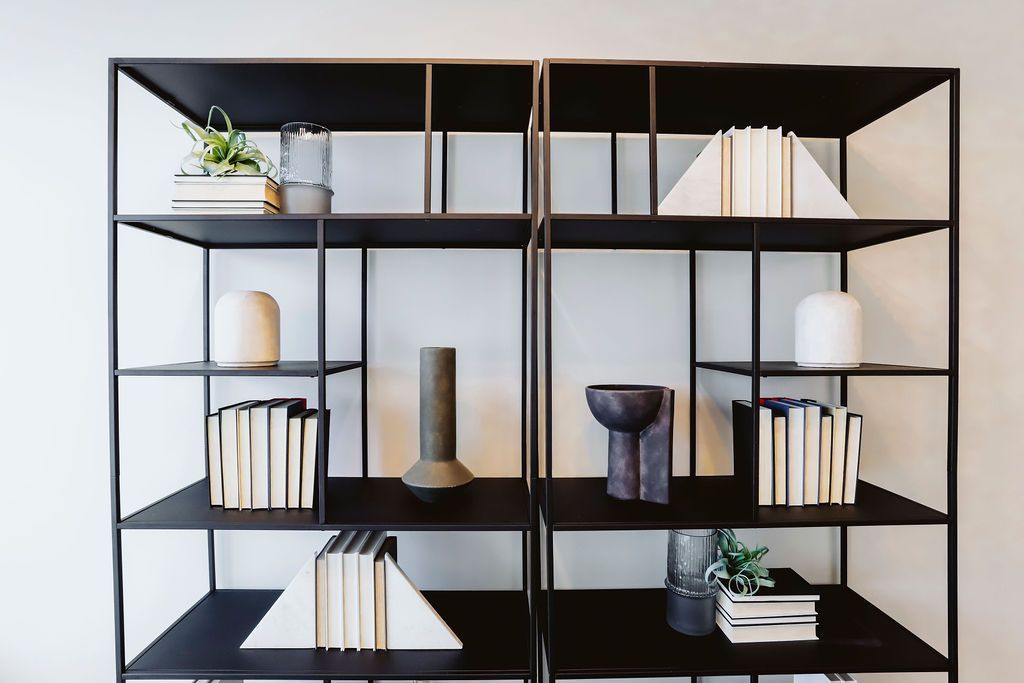 A bookshelf with a lot of books and vases on it