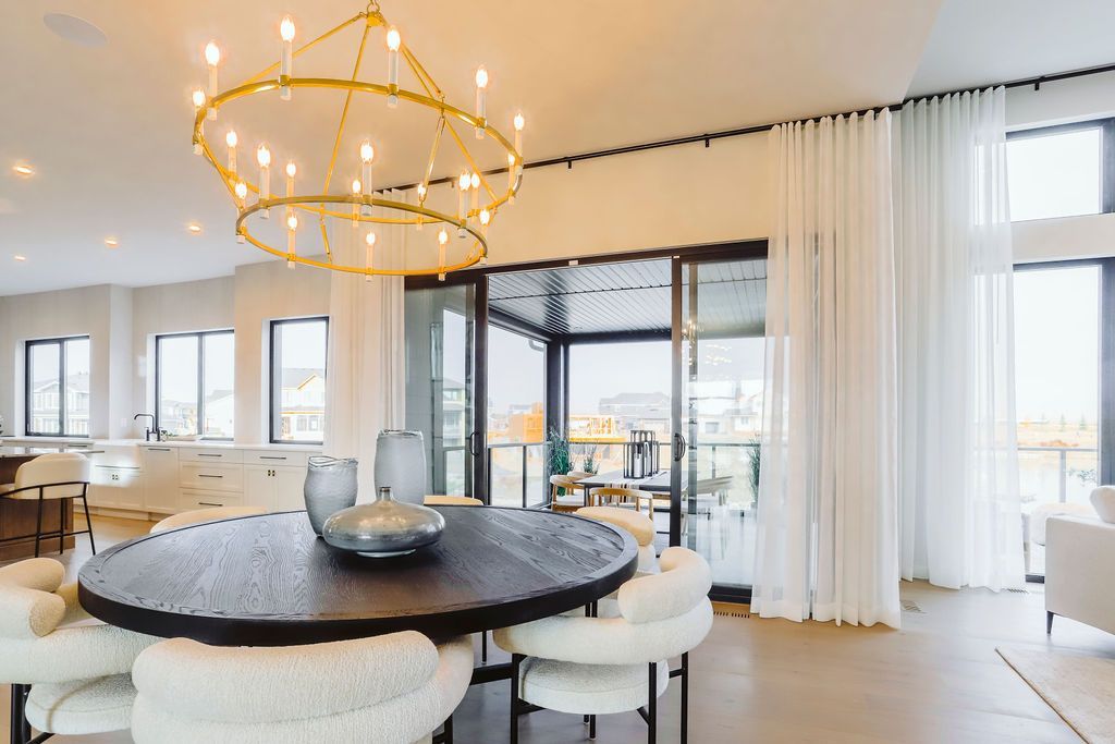 A dining room with a round table and white chairs and a chandelier.