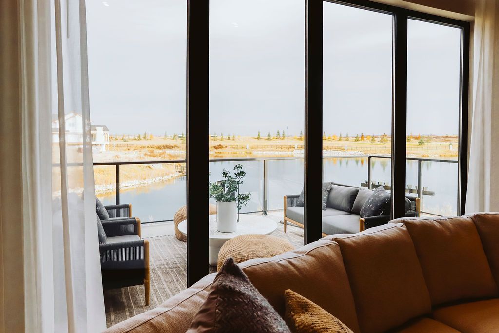 A living room with a couch and a balcony with a view of the ocean.