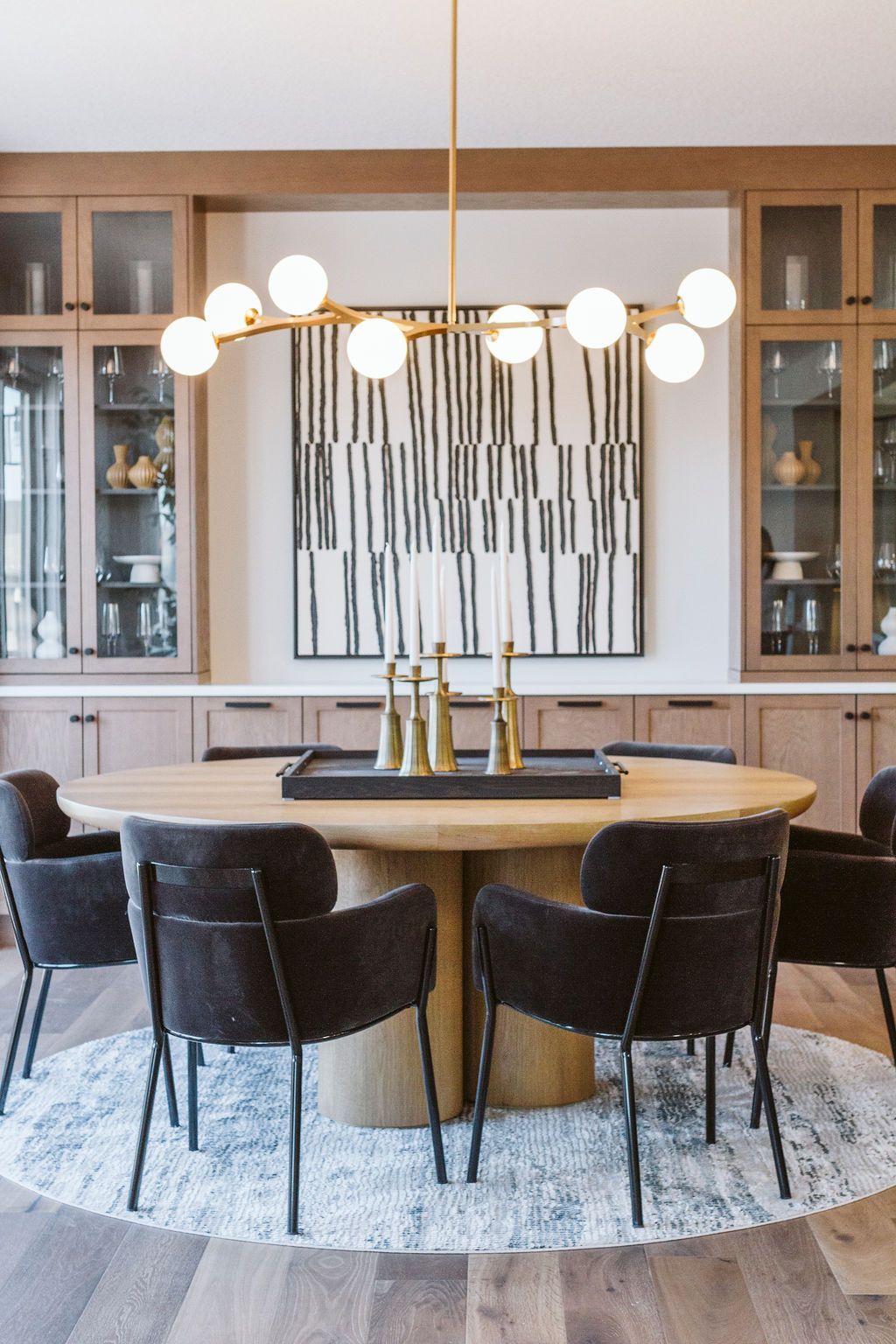 A dining room with a round table and chairs and a chandelier.