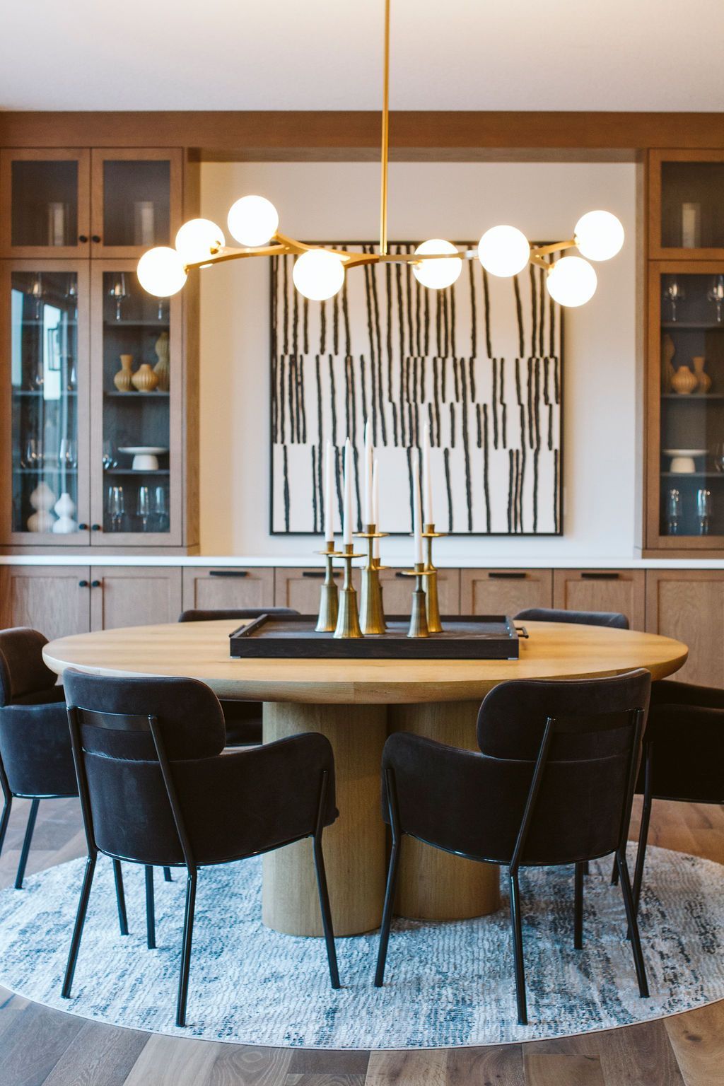 A dining room with a round table and chairs and a chandelier.