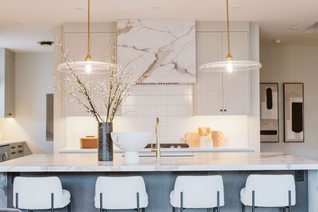 A kitchen with a large island , stools , and a sink.
