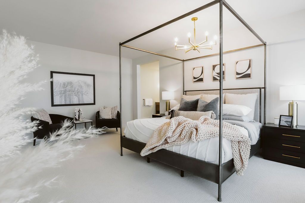 A bedroom with a four poster bed and a chandelier.