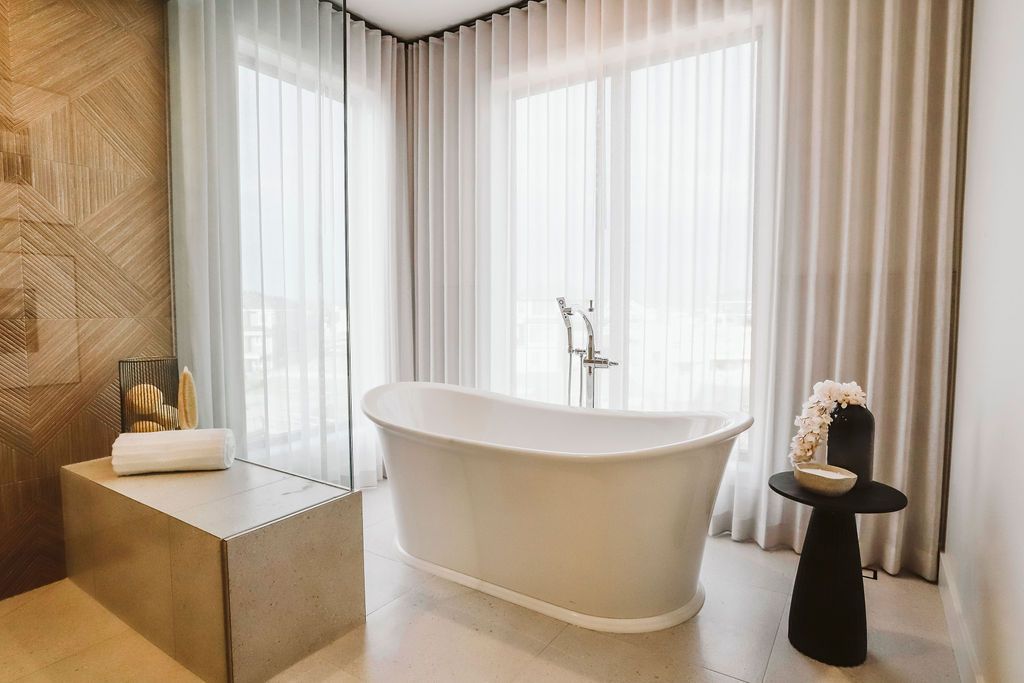 A bathroom with a bathtub and a table in front of a window.