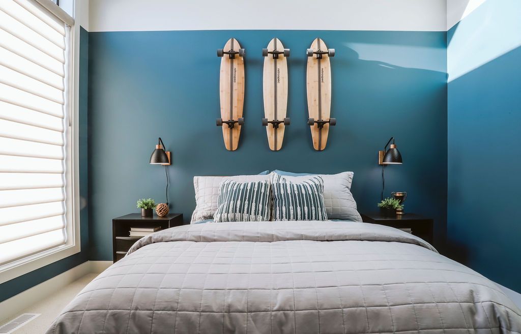A bedroom with a bed and surfboards on the wall.