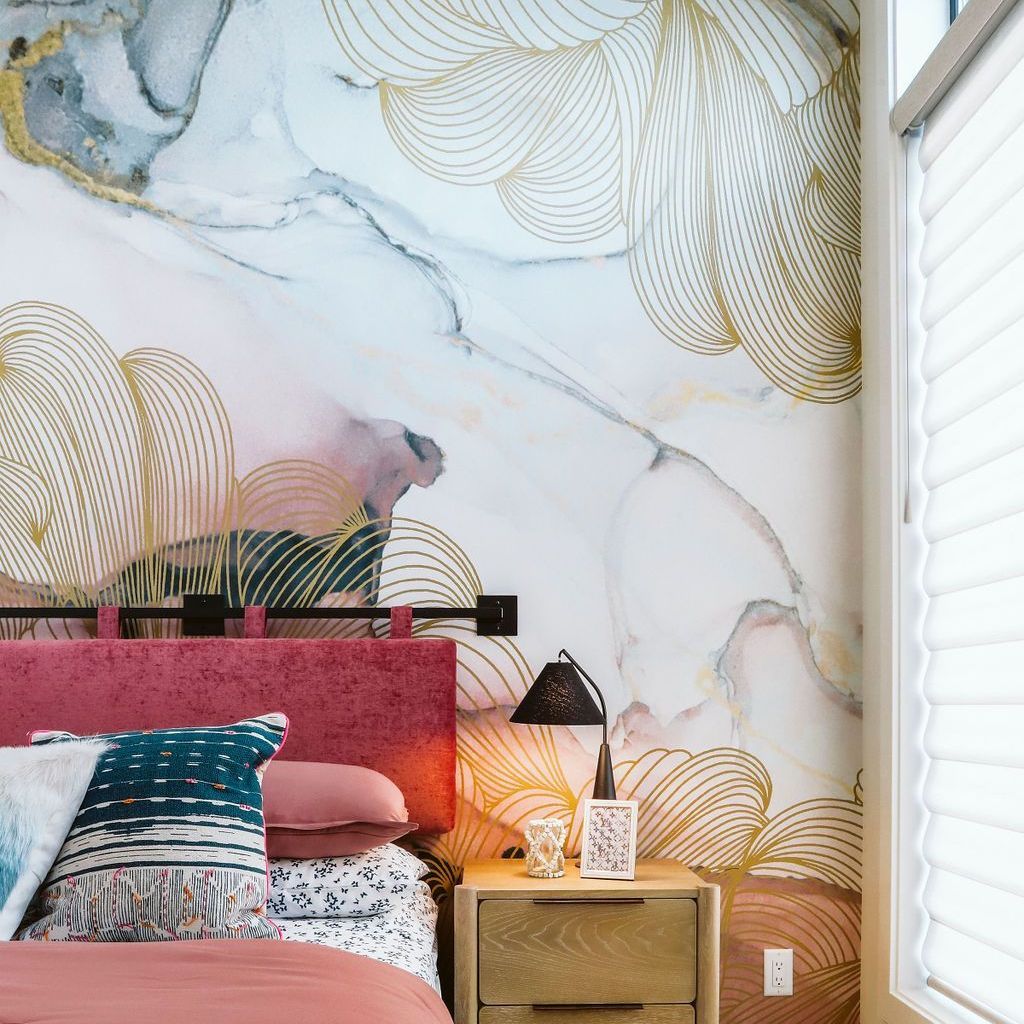 A bedroom with a bed , nightstand , lamp and marble wall mural.