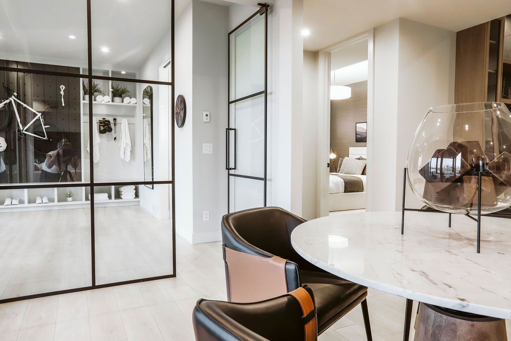 A dining room with a table and chairs and a glass door.