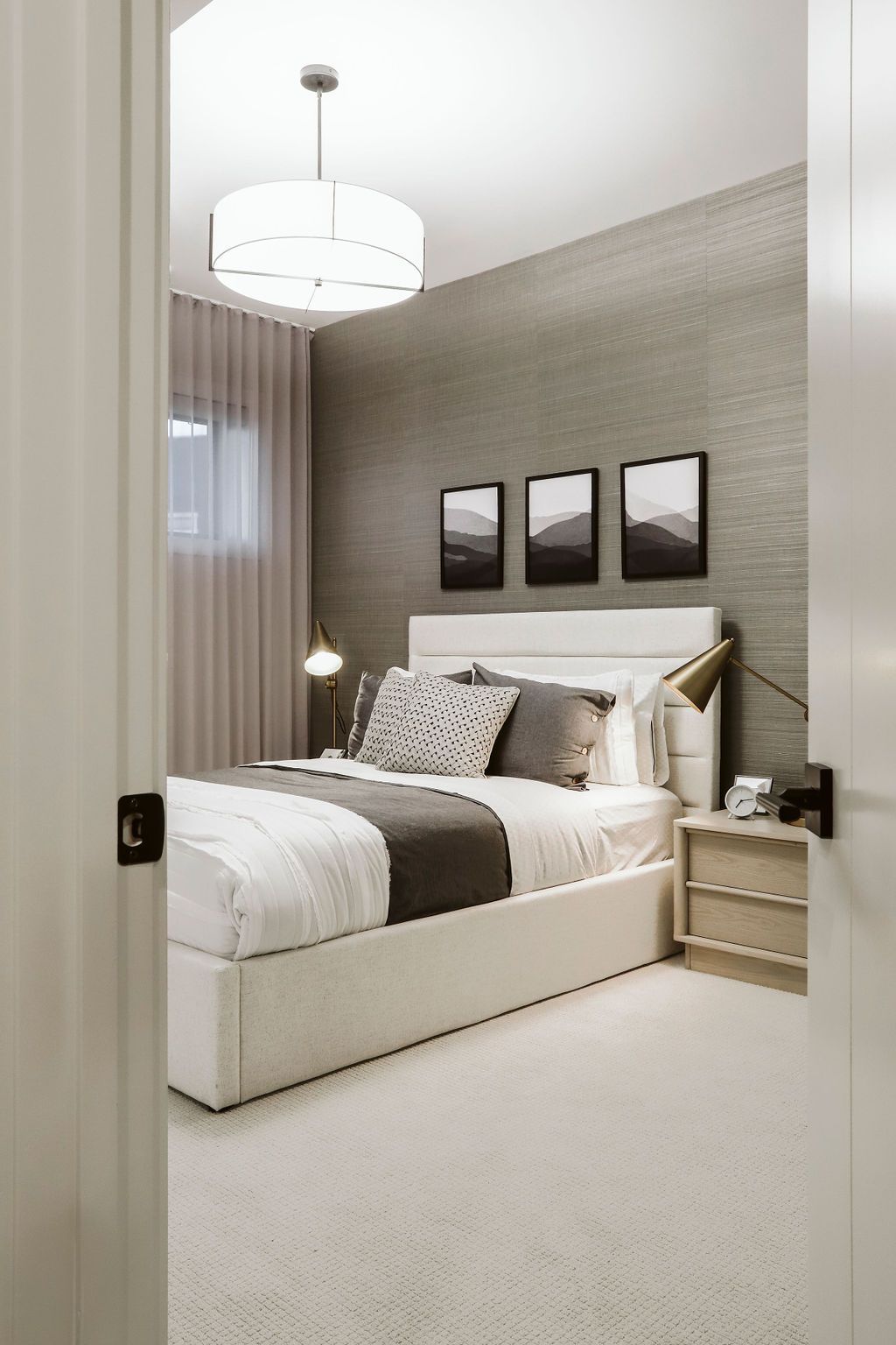 A bedroom with a bed , nightstand , lamps and pictures on the wall.