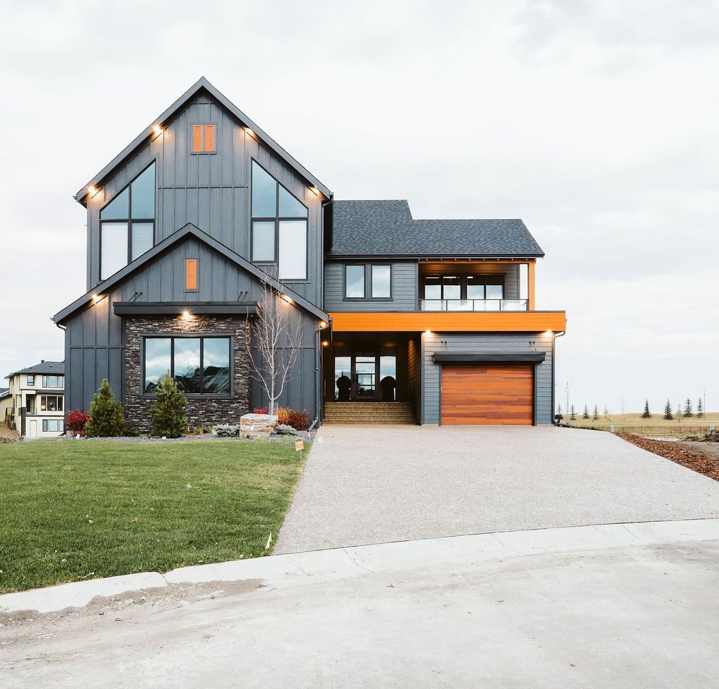 A large house with a lot of windows is sitting on top of a lush green field.