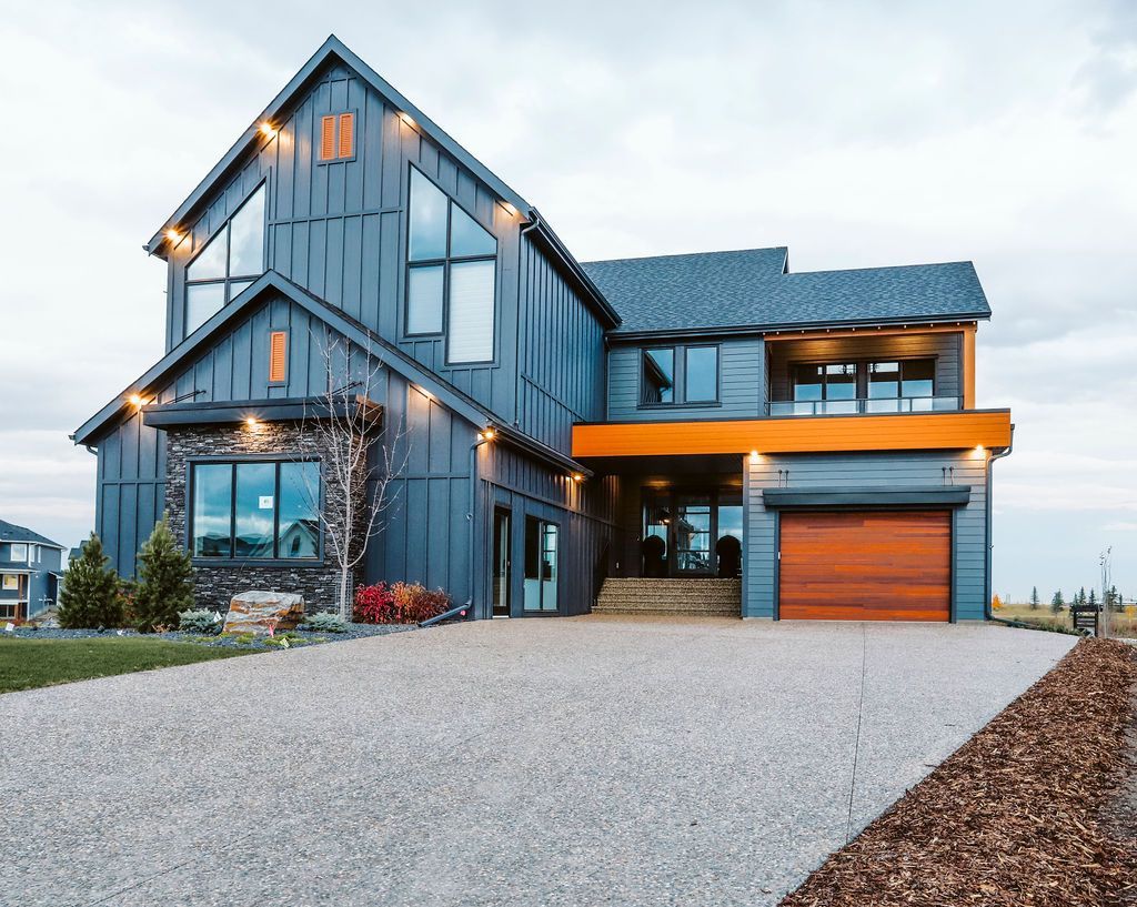 A large blue and orange house with a gravel driveway in front of it.