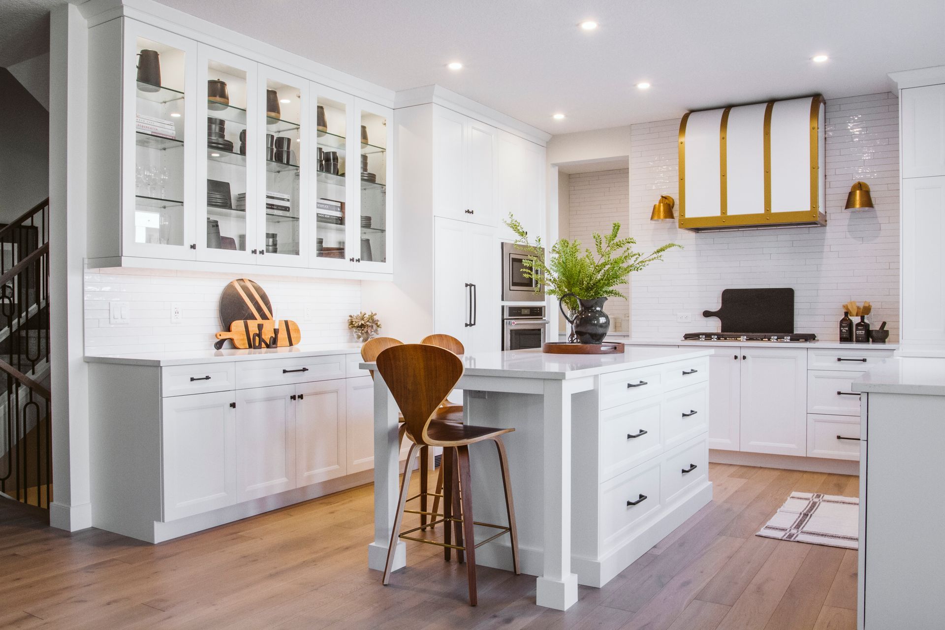 A kitchen with white cabinets , wooden floors , and a large island.
