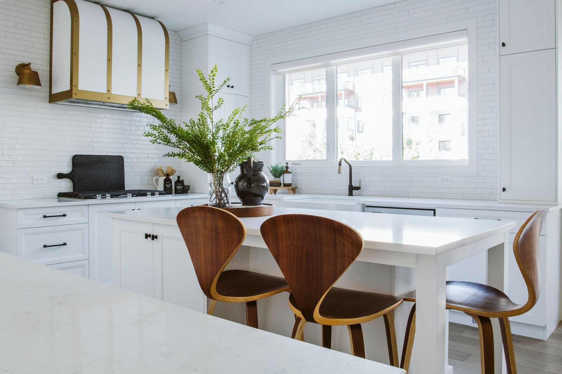 A kitchen with white cabinets and wooden chairs and a table.