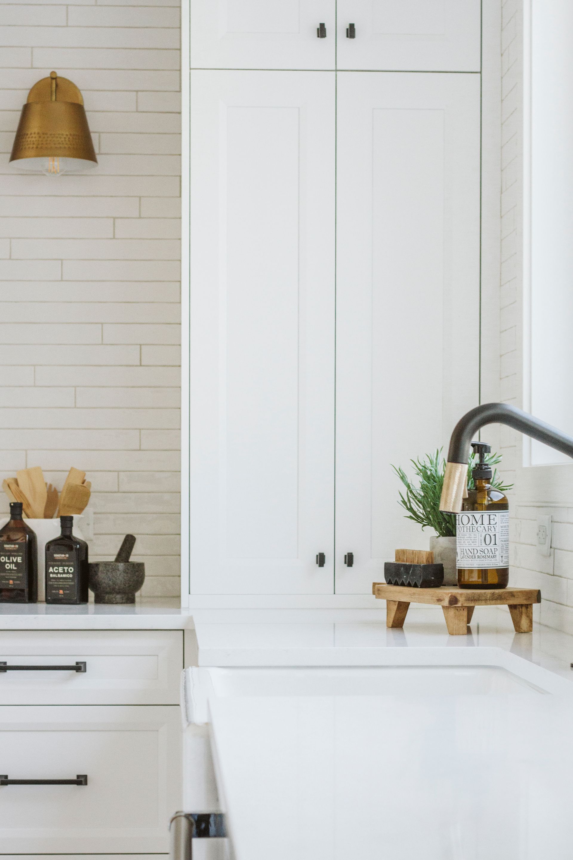 A kitchen with white cabinets , a sink , and a faucet.