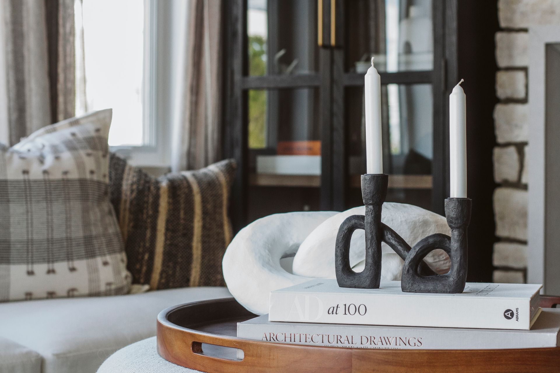 A living room with a couch , books , candles and a tray.