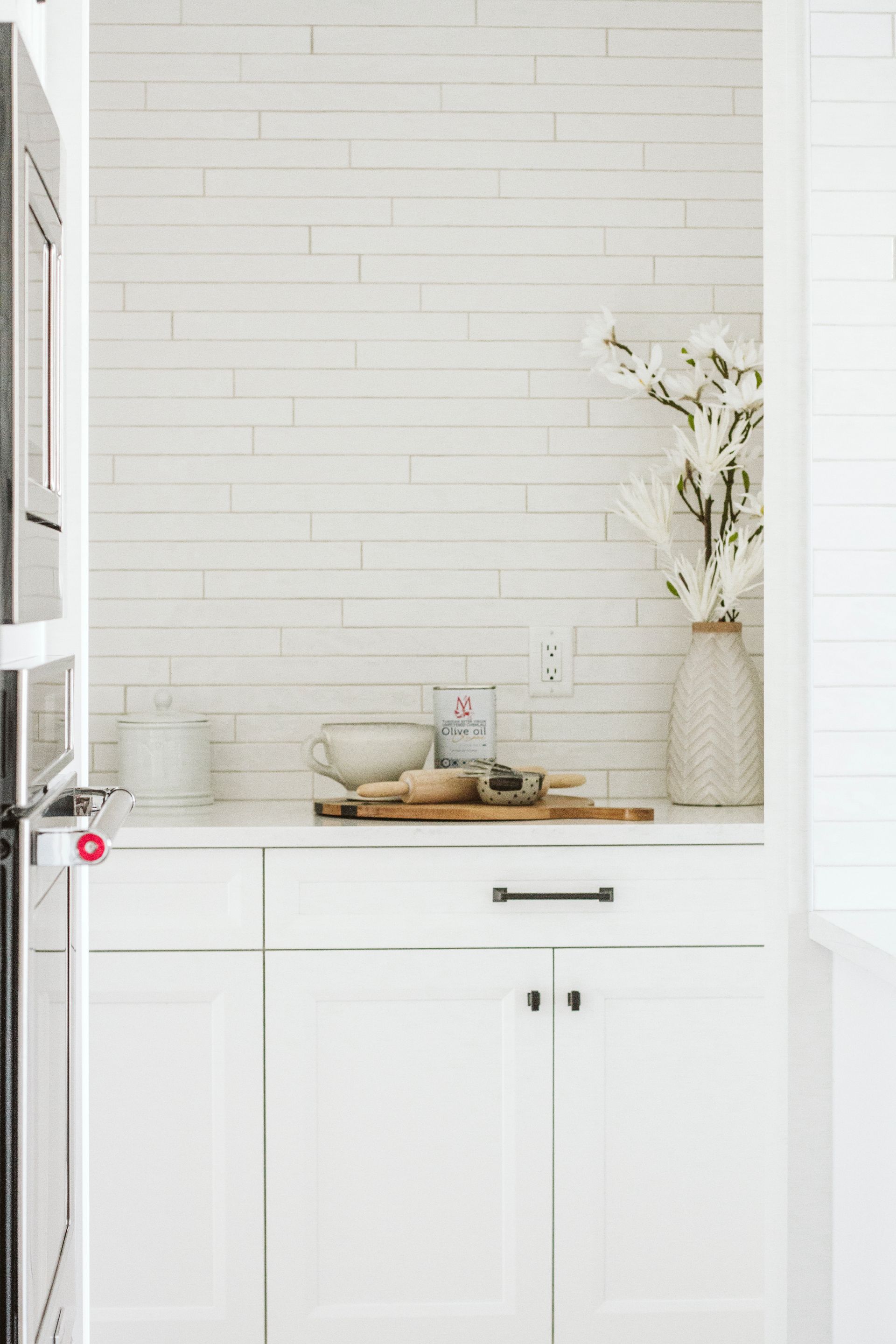 There is a vase of flowers on the counter in the kitchen.