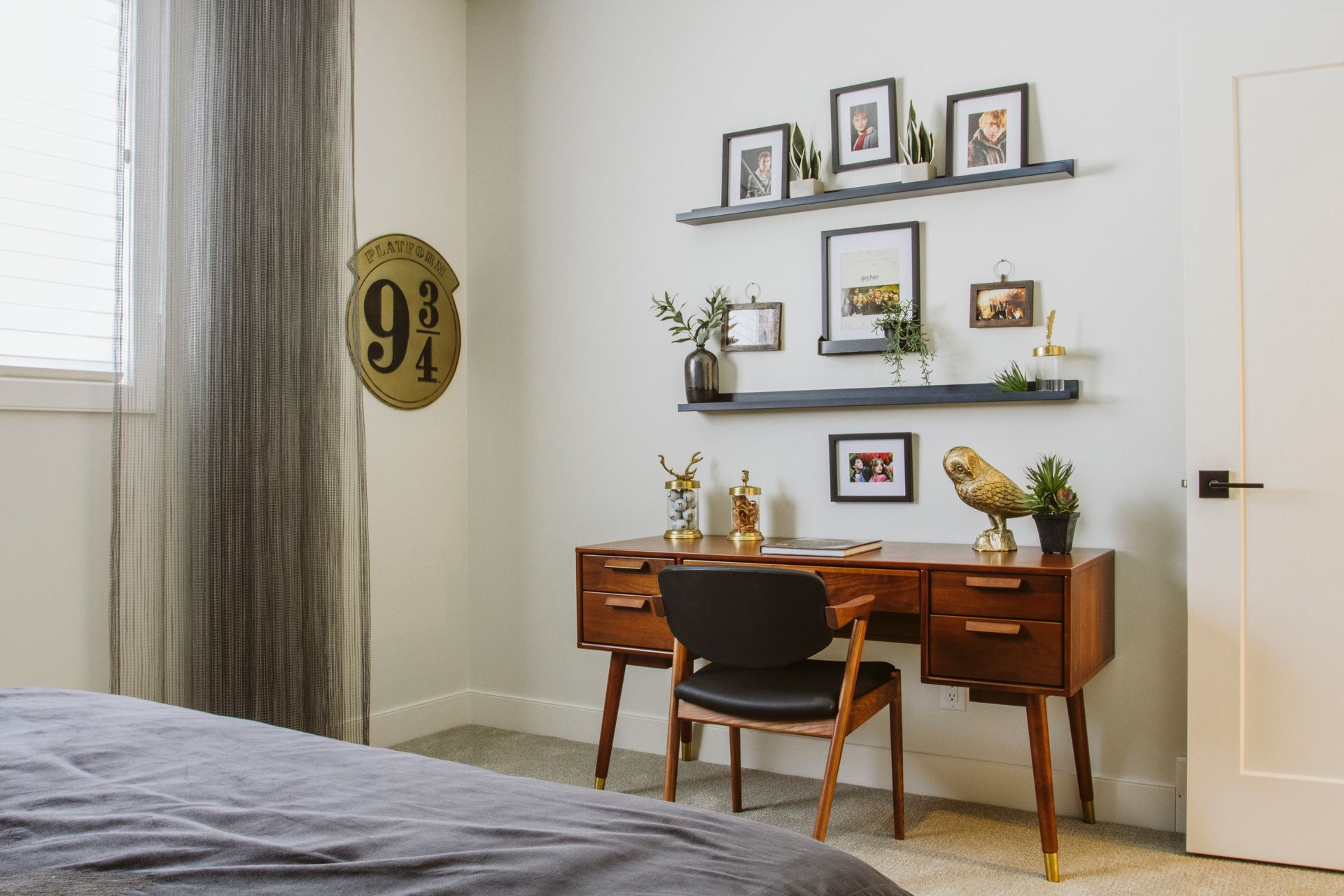 A bedroom with a desk , chair and shelves.