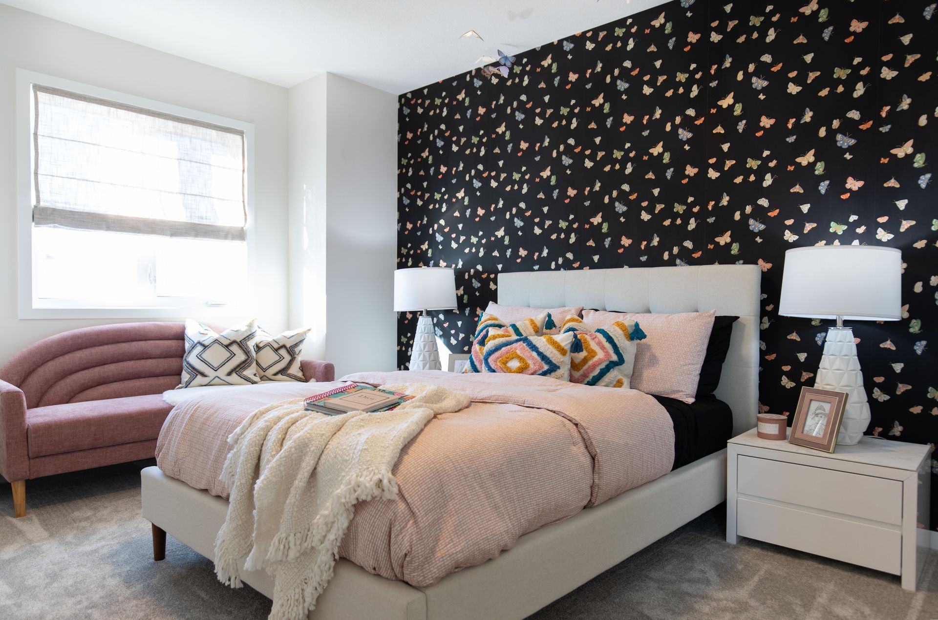 A bedroom with a bed , couch , nightstand and lamps.