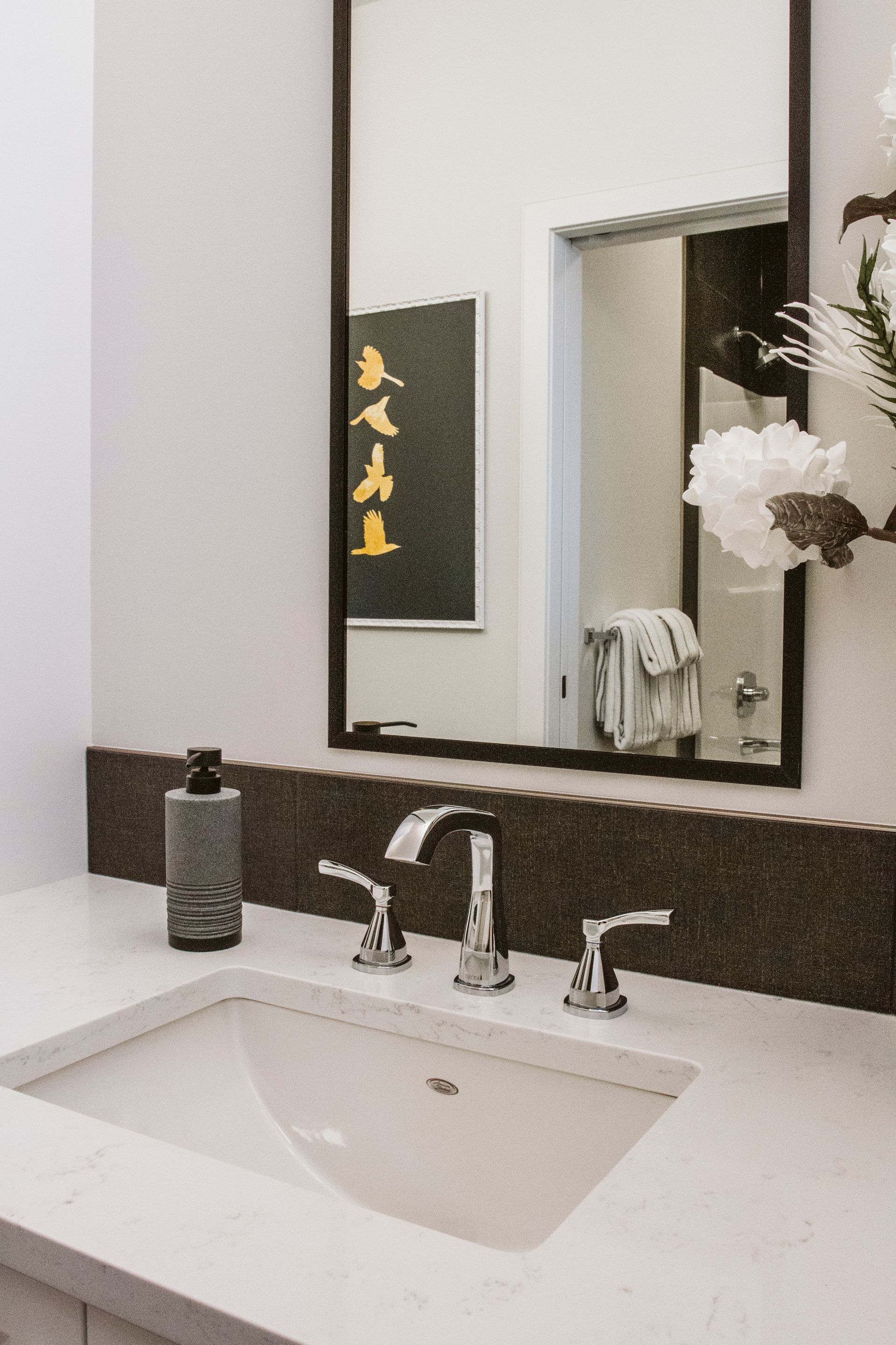 A bathroom with a sink , mirror and soap dispenser.