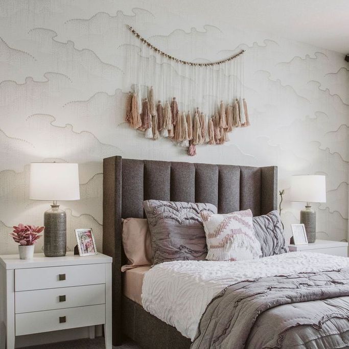 A bedroom with a bed , nightstand , lamps and a wall hanging