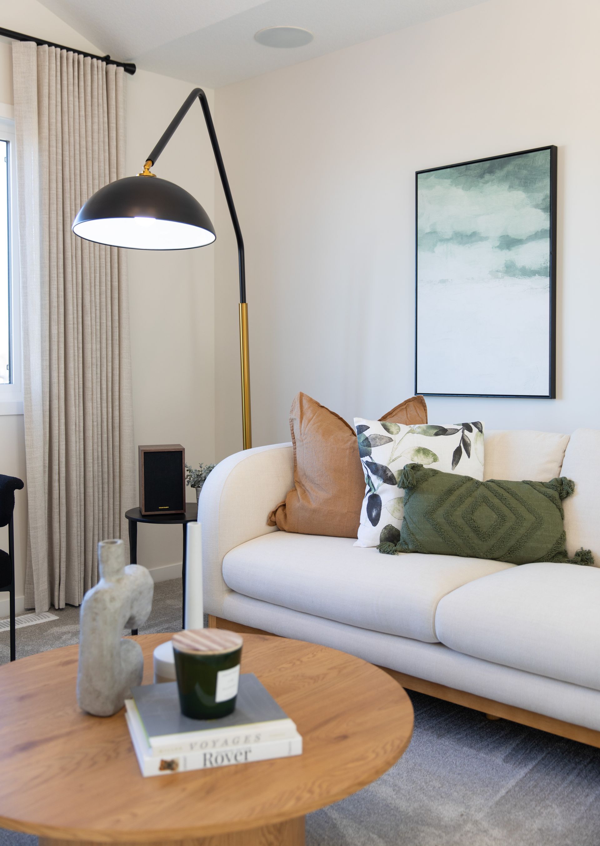 A living room with a couch , coffee table , lamp and painting on the wall.