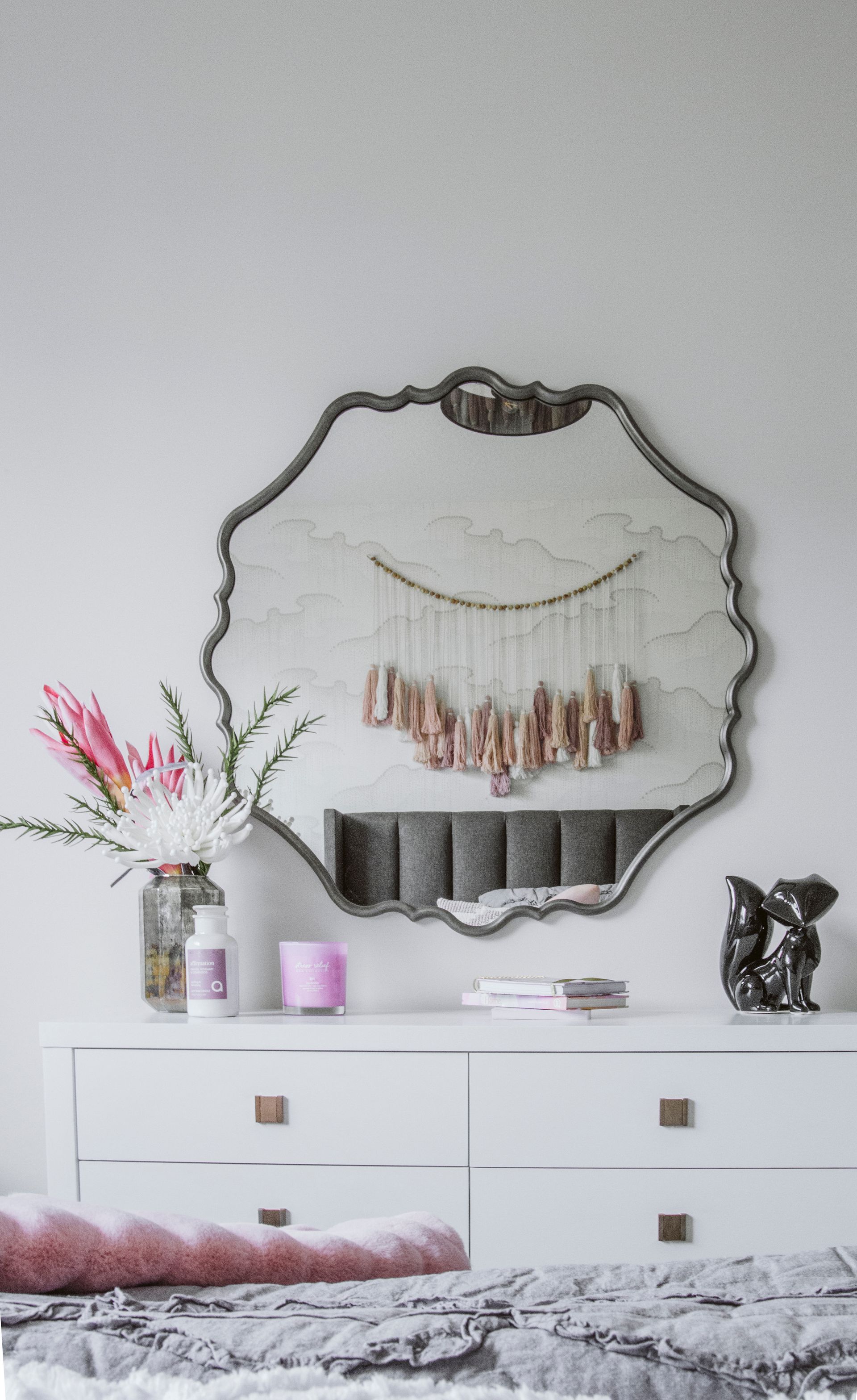 A bedroom with a large mirror on the wall above a dresser.