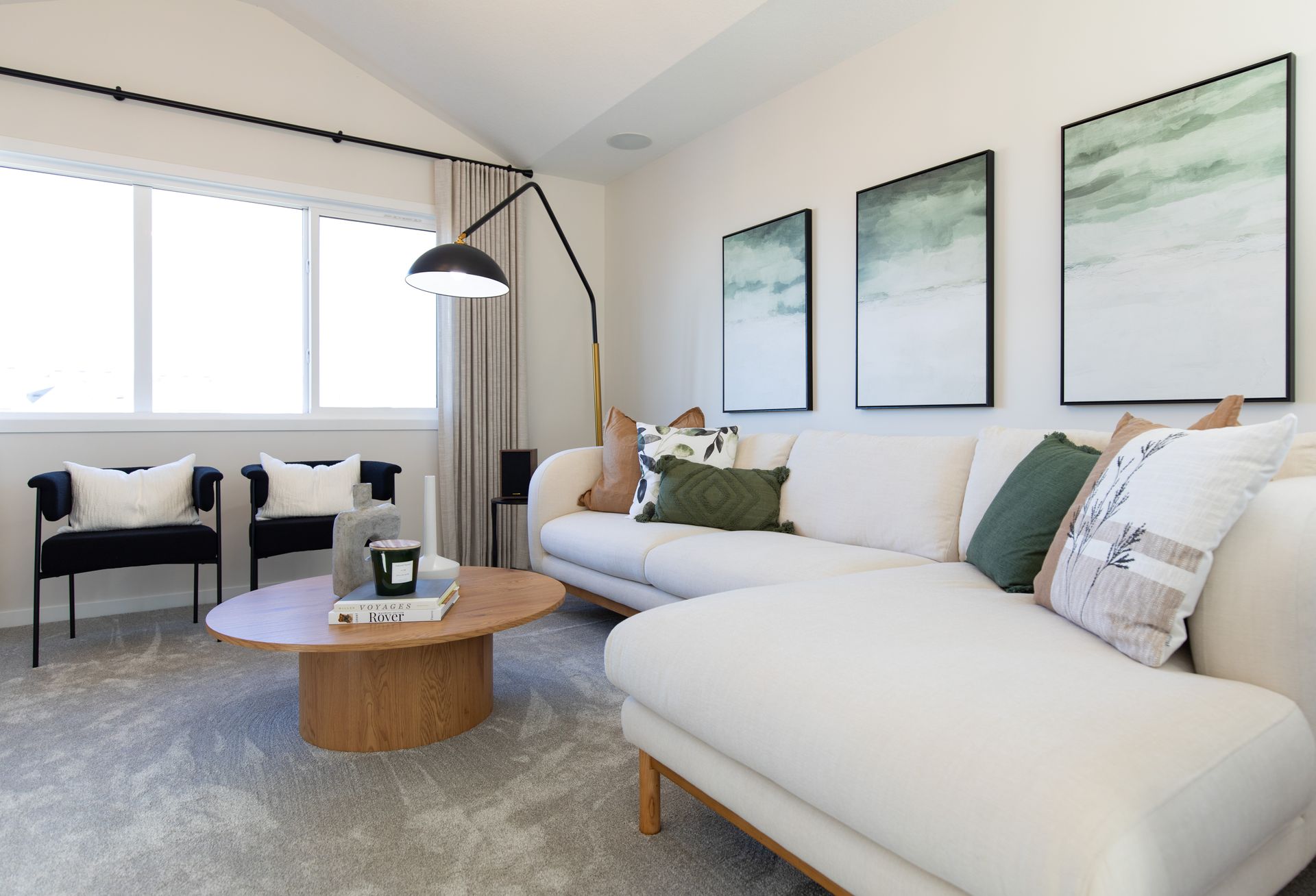 A living room with a couch , chairs , coffee table and paintings on the wall.