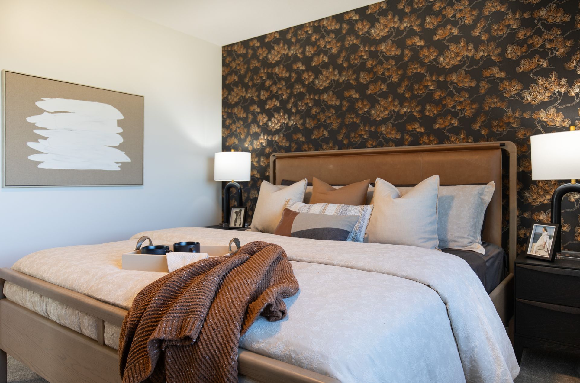 A bedroom with a bed , nightstand , lamps and a painting on the wall.