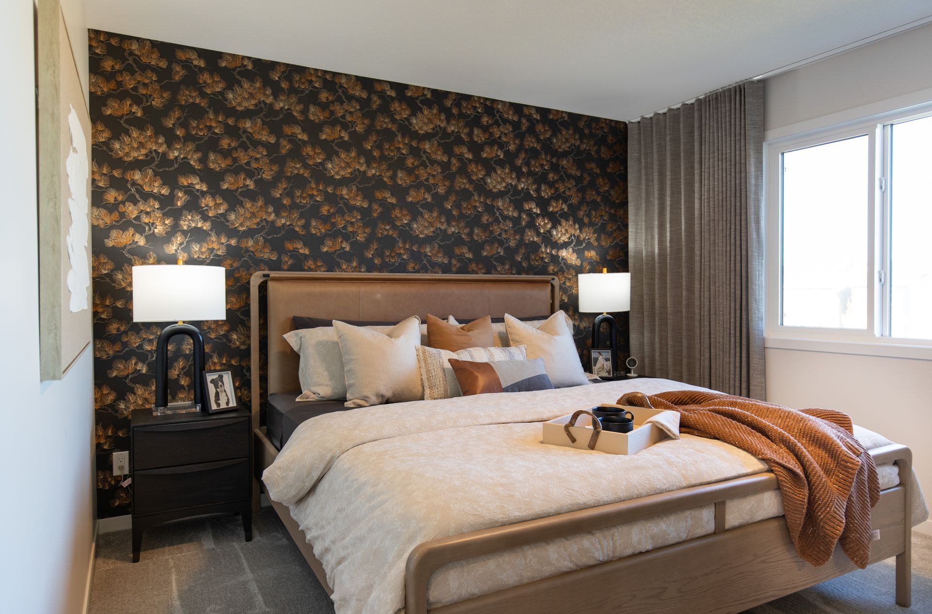 A bedroom with a large bed , nightstands , lamps and a window.