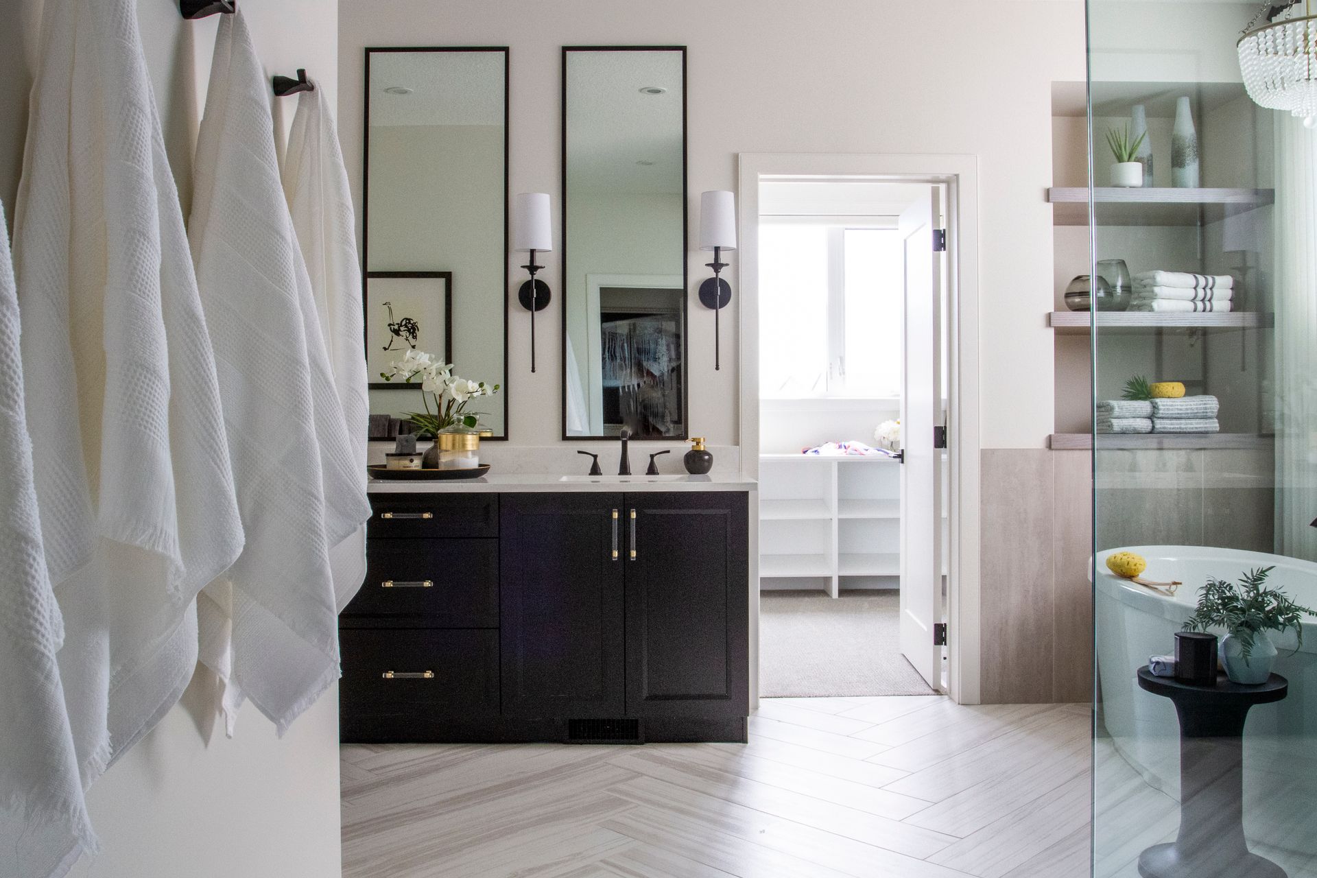 A bathroom with two sinks , two mirrors , a tub and a walk in shower.