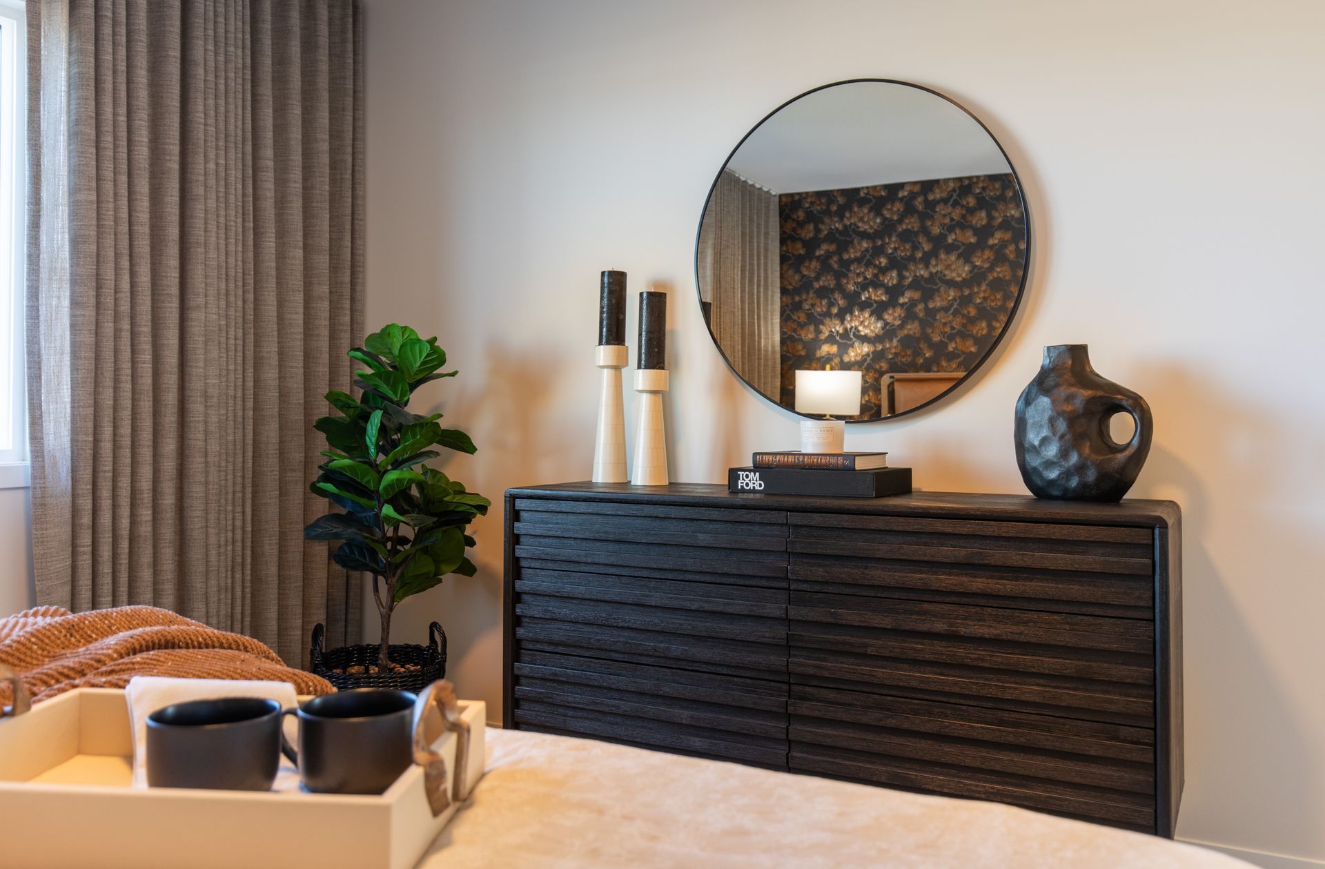 A bedroom with a bed , dresser , mirror and vases.
