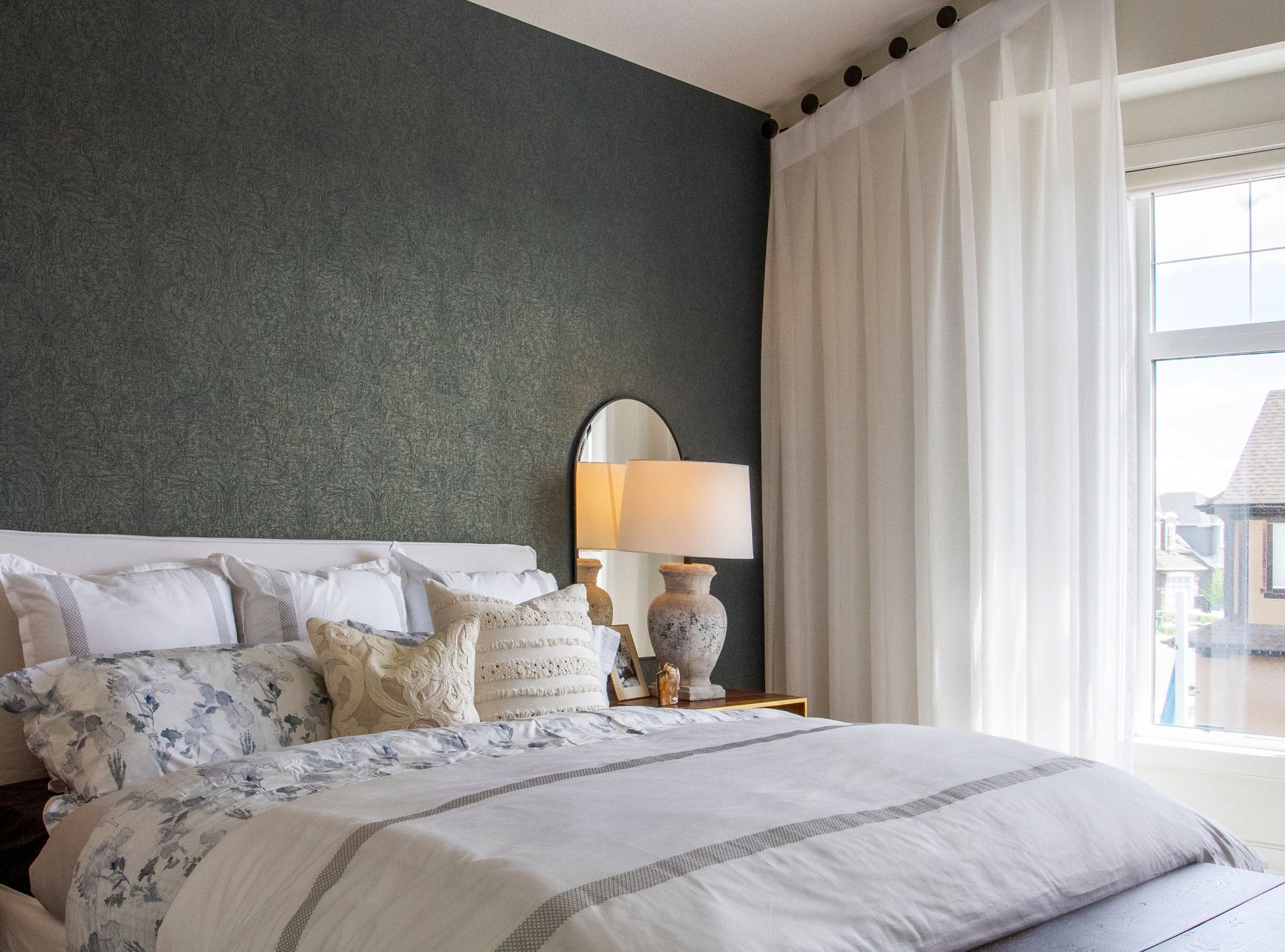 A bedroom with a bed , lamps , a mirror and a window.