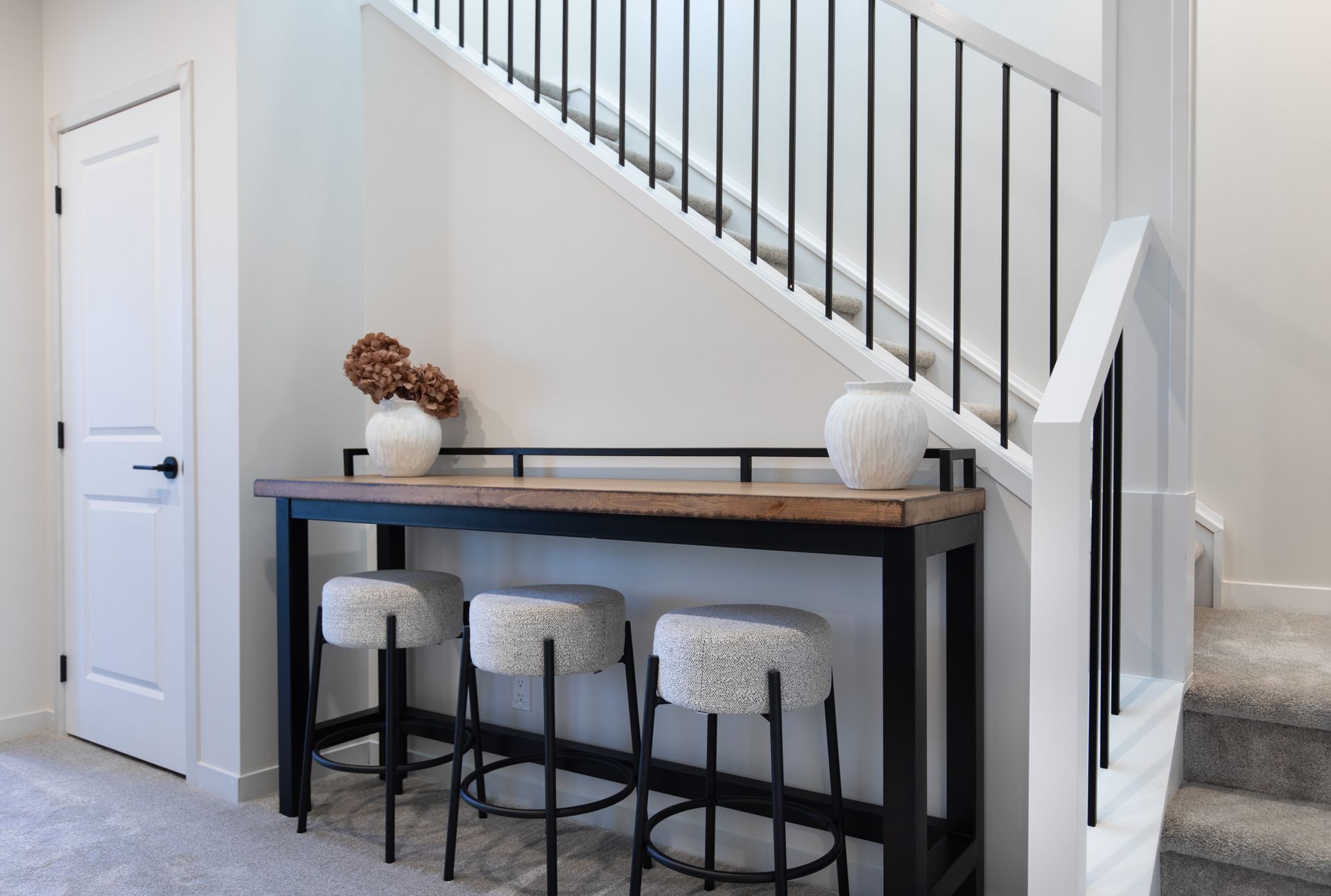 There is a table and stools under the stairs.