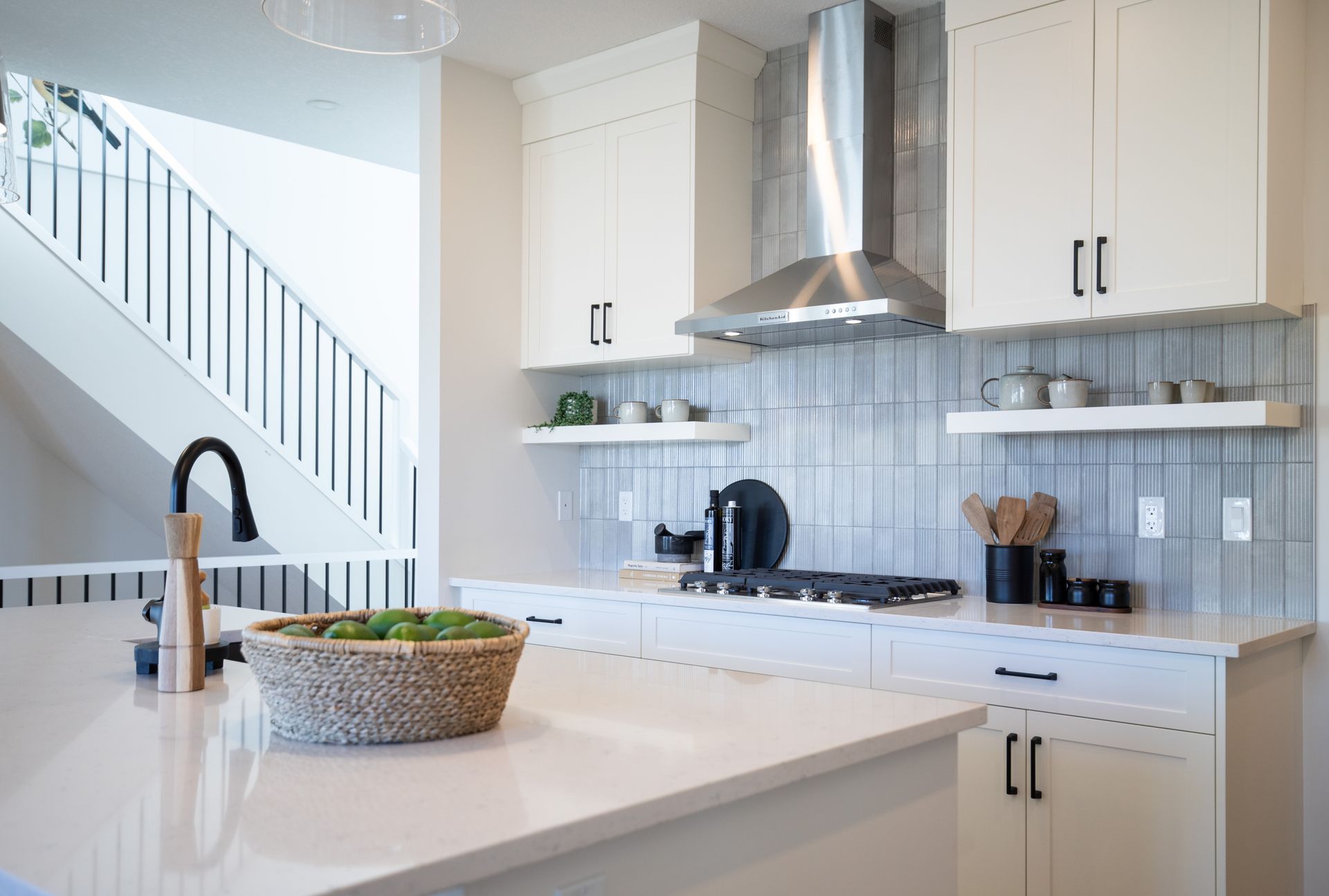 A kitchen with white cabinets , a stove , a sink and a staircase.