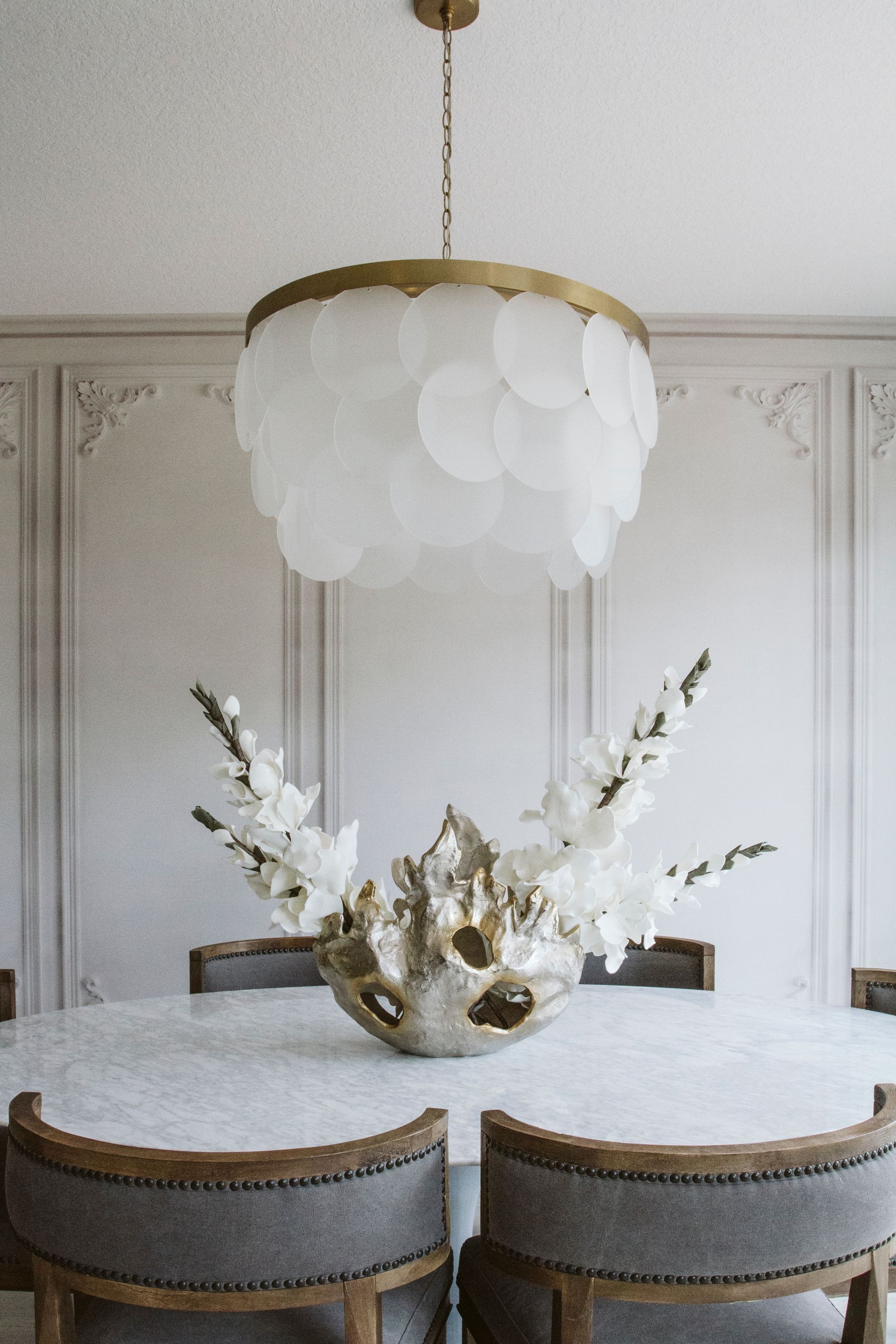 A dining room with a table and chairs and a chandelier hanging from the ceiling.