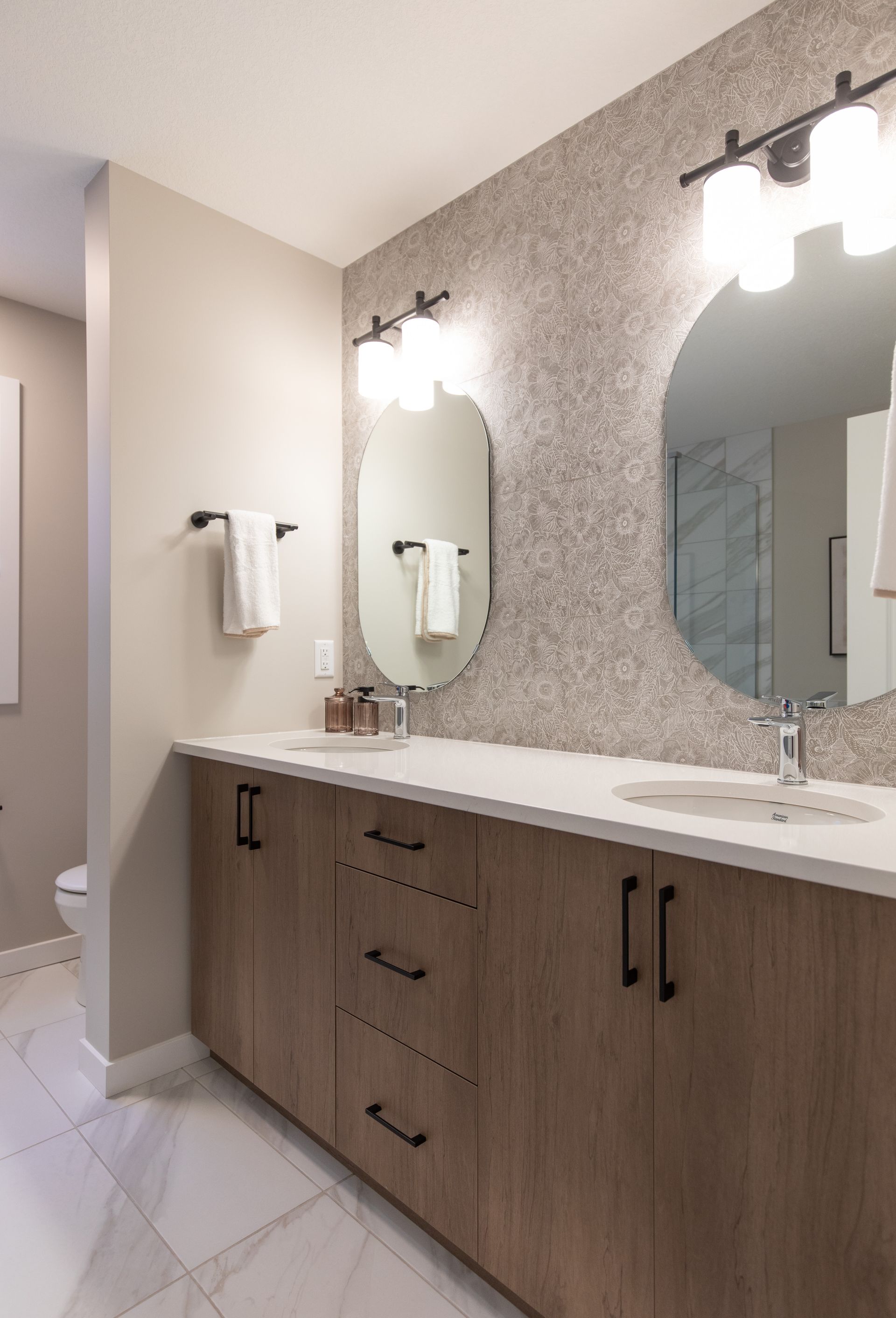 A bathroom with two sinks , a toilet and a large mirror.