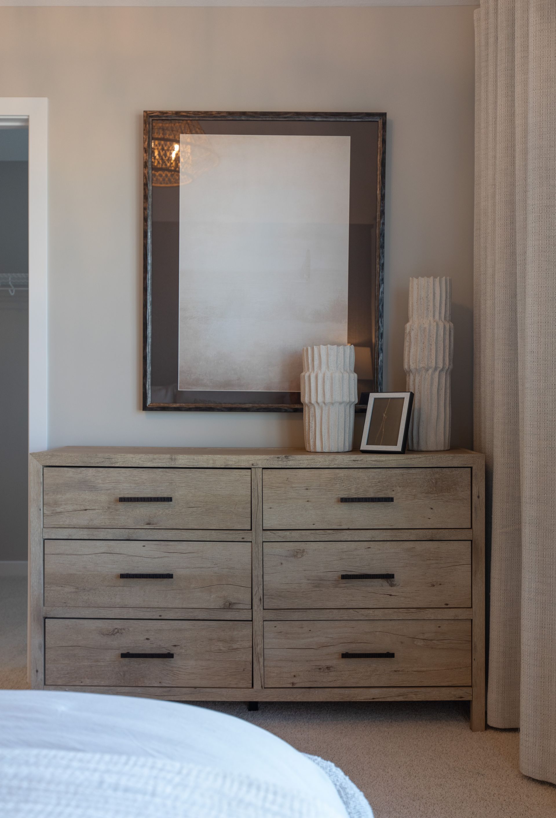 A bedroom with a dresser and a mirror above it.