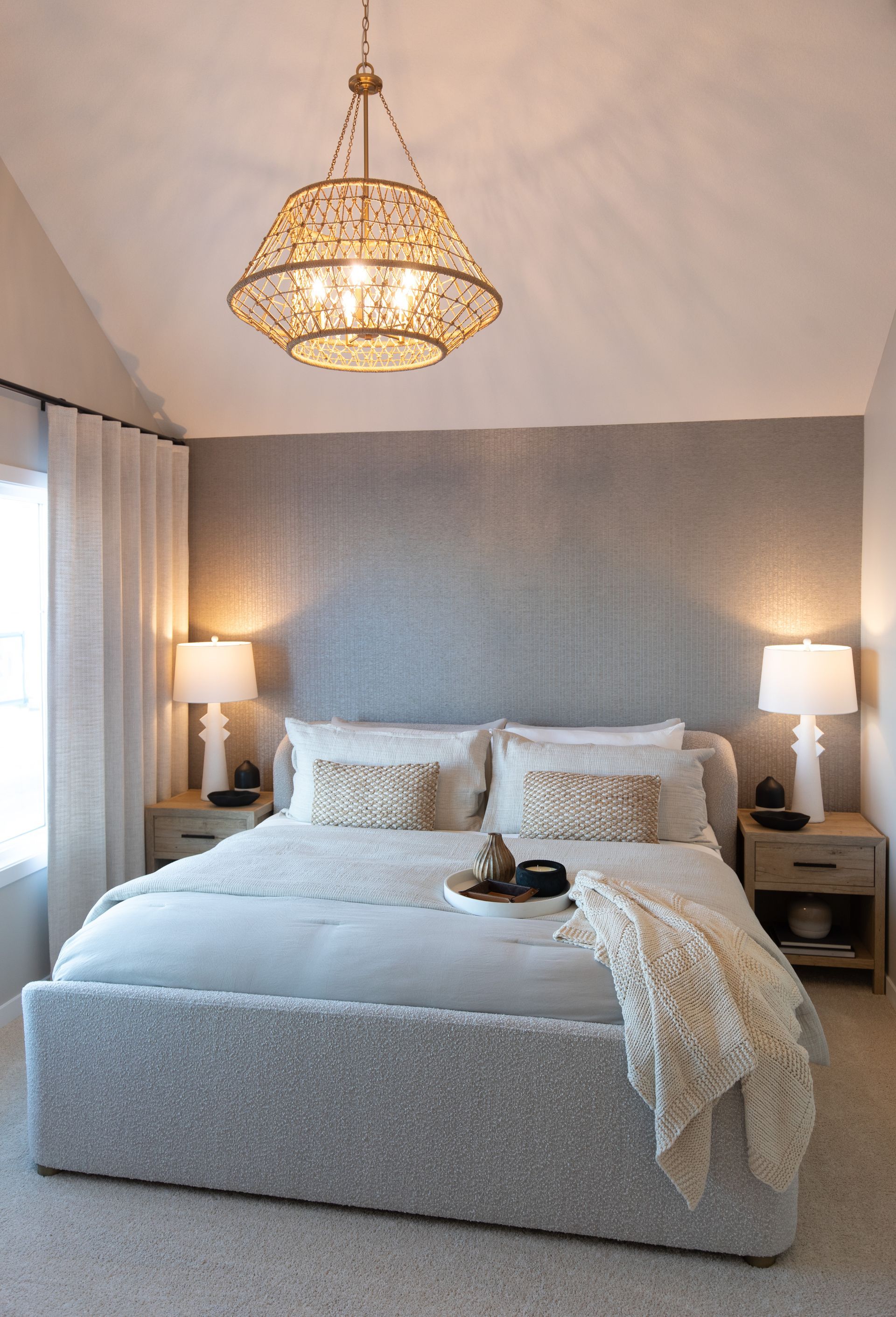 A bedroom with a large bed and a chandelier hanging from the ceiling.