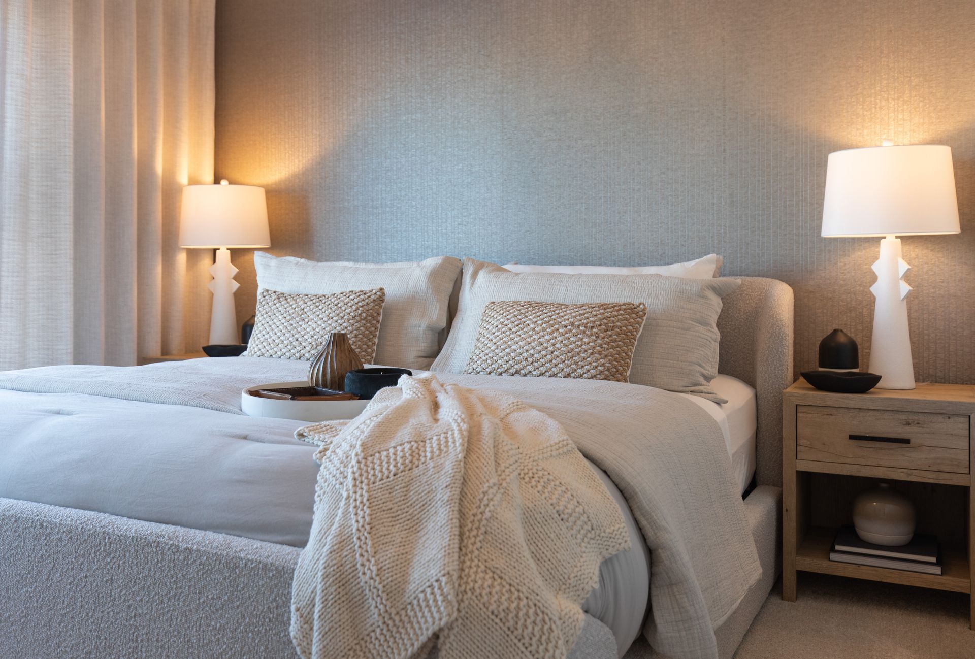 A bedroom with a bed , two lamps and a nightstand.