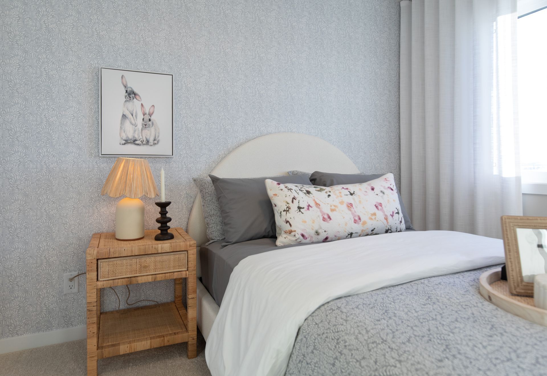 A bedroom with a bed , nightstand , lamp and picture on the wall.