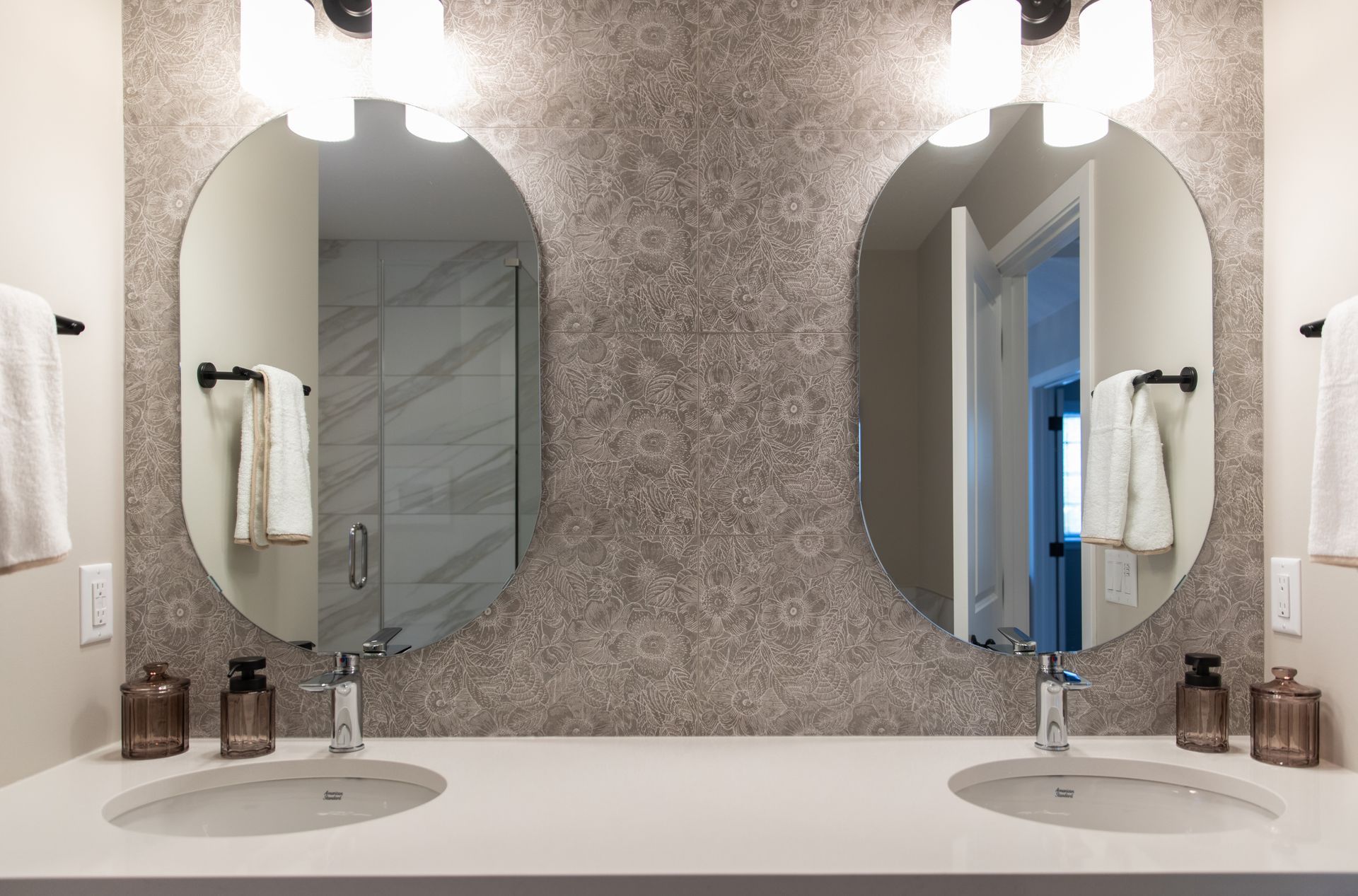 A bathroom with two sinks and two round mirrors.