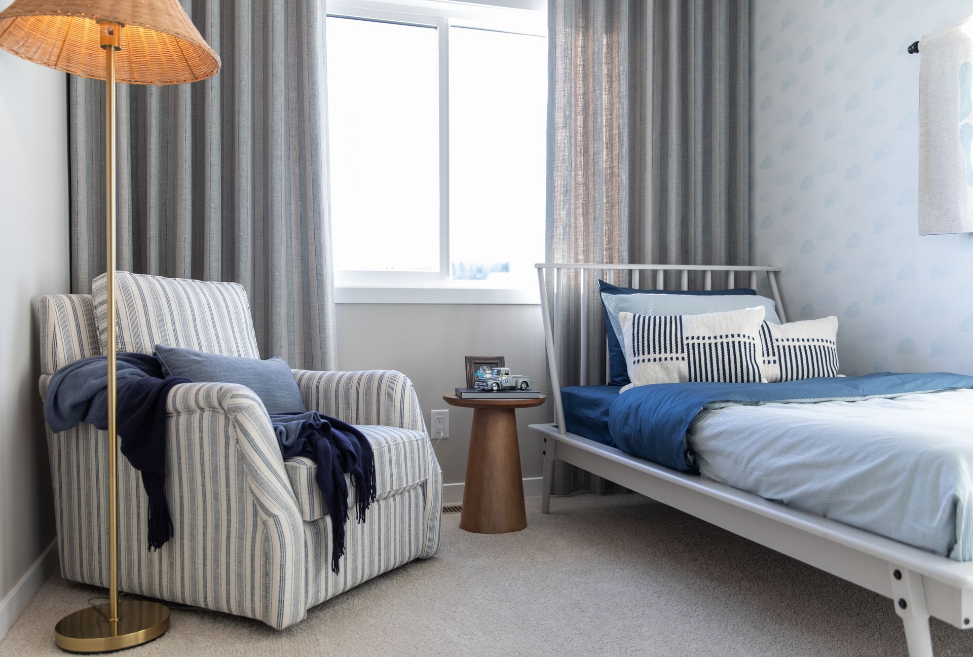 A bedroom with a bed , chair , lamp and window.
