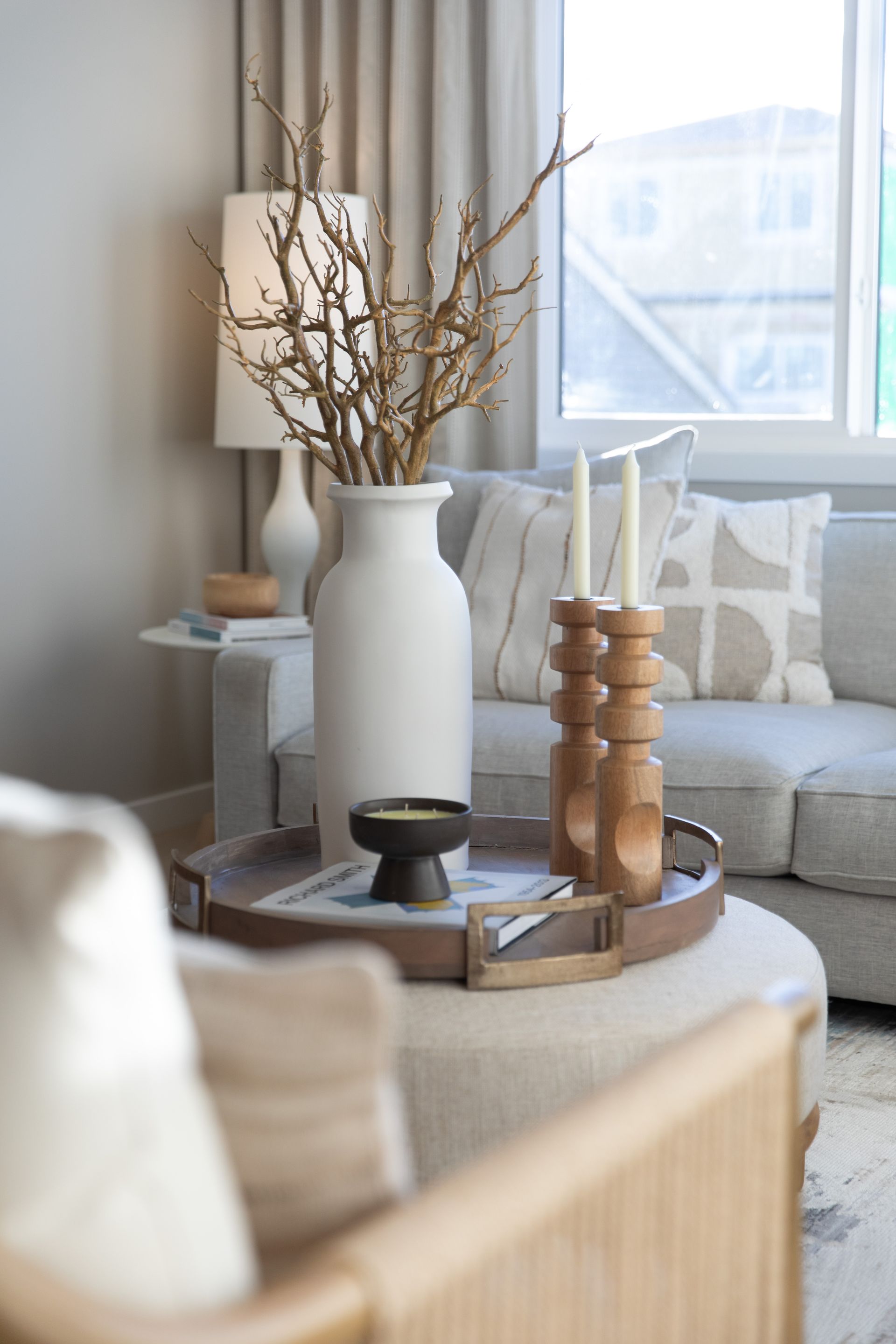 A living room with a couch , chair , table , vase and candles.
