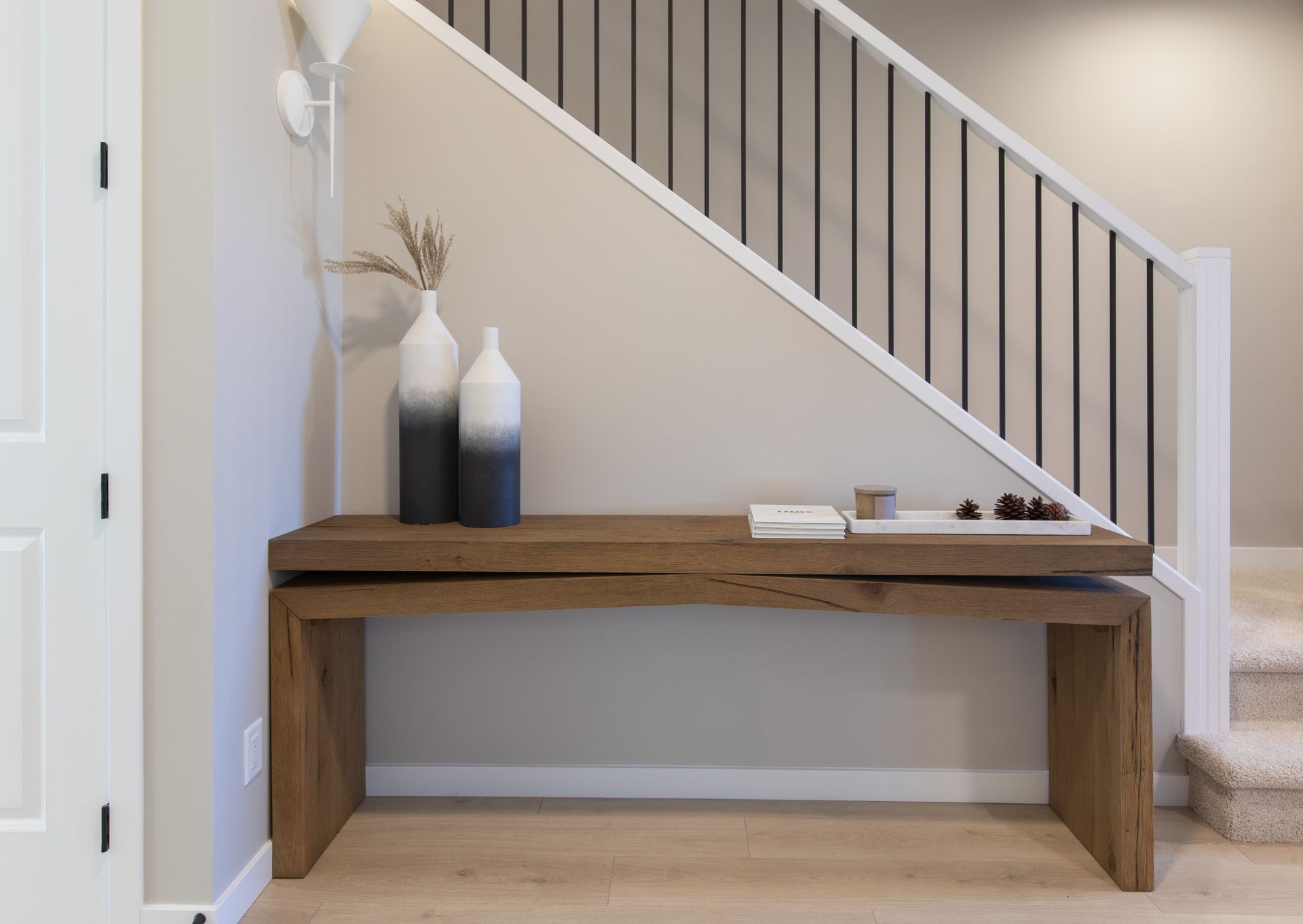 A wooden bench is under a staircase in a hallway.
