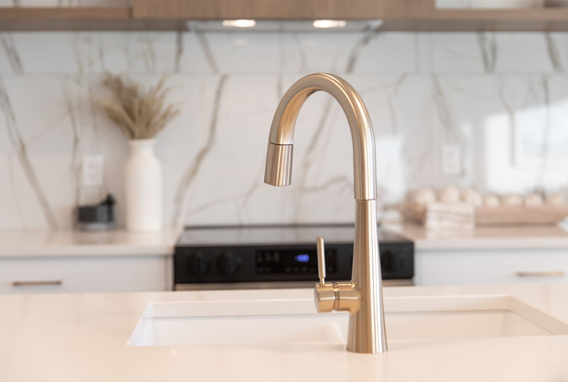 A kitchen sink with a faucet and a stove in the background.